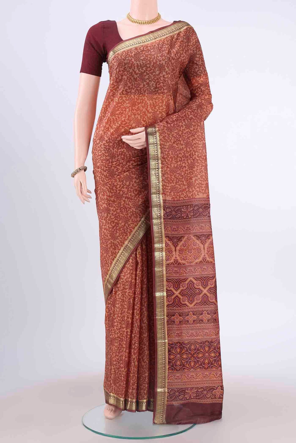 Rust Printed Silk Saree with Floral Print on the body and Zari Border displayed on a mannequin