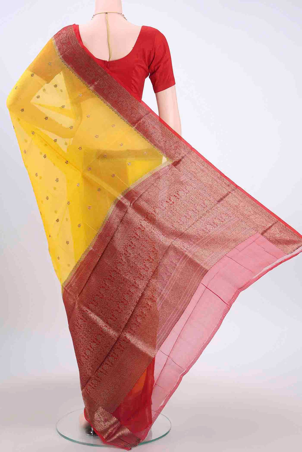 Flat view of Yellow Organza Silk Saree with Zari Butta on the body and Zari Border
