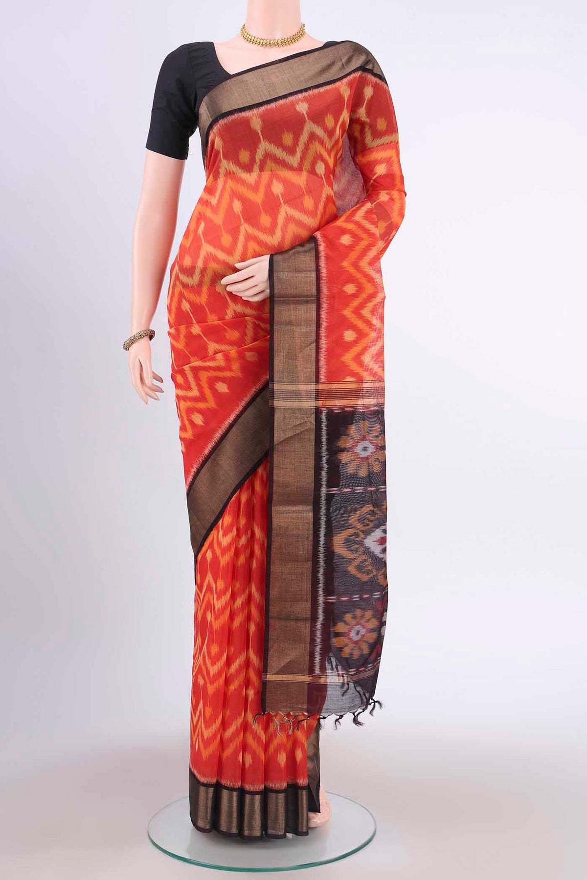 Brick Orange Kora Cotton Saree with Ikat Print on the body and Zari Border displayed on a mannequin