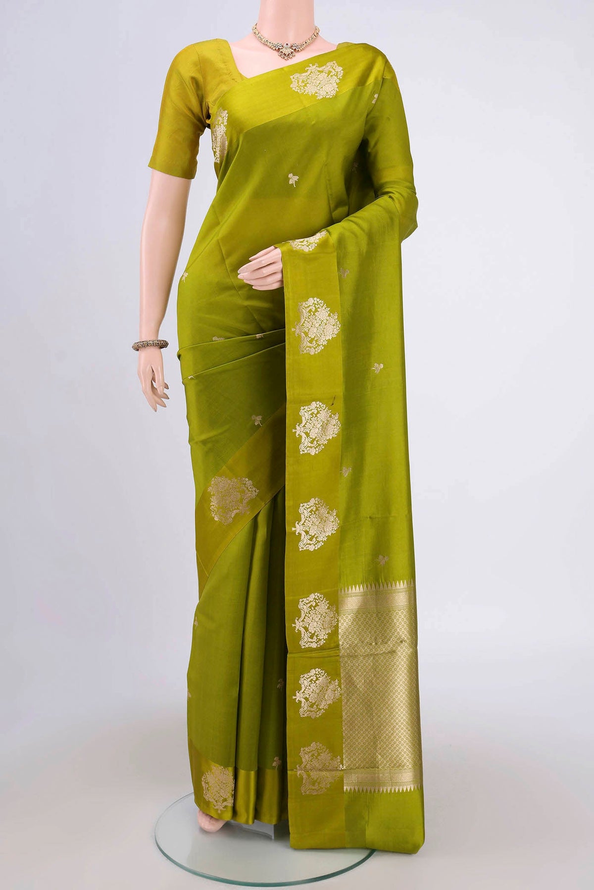 Parrot Green Banarasi Katan Silk Saree with Zari Butta on the body and Zari Border.  displayed on a mannequin