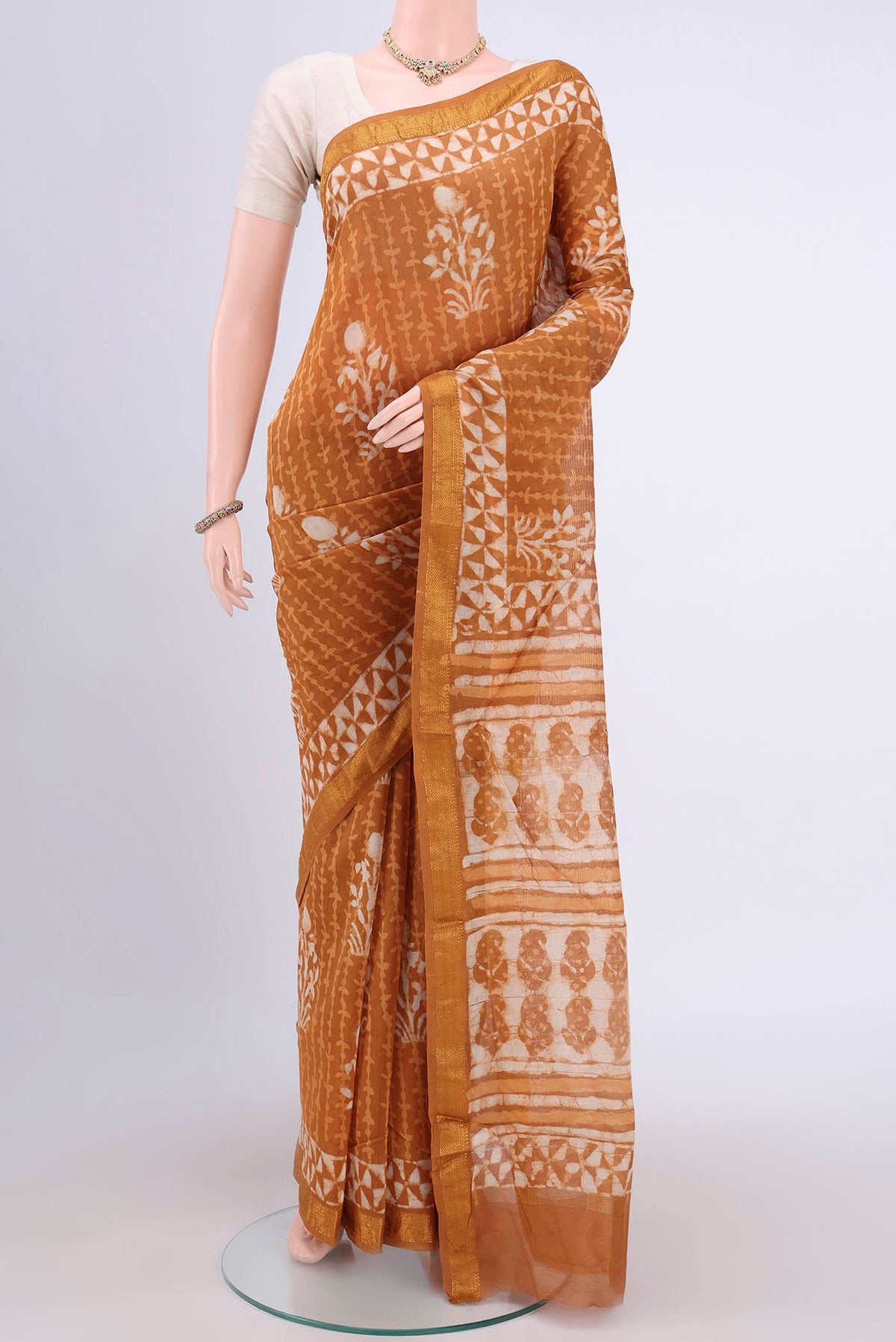 Rust Maheshwari Silk Cotton Saree with Printed design on the body and Zari Border.  displayed on a mannequin