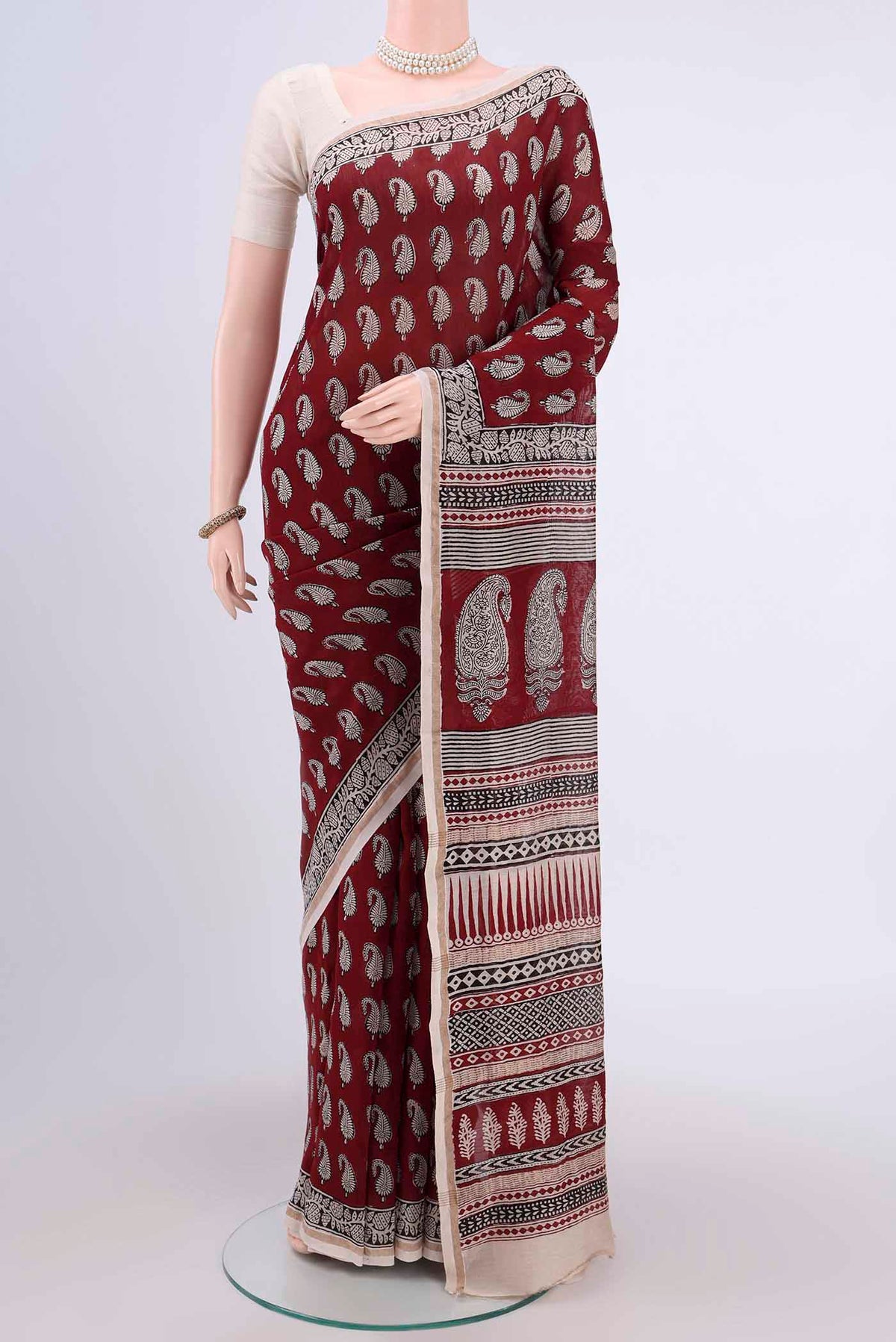 Maroon Maheshwari Silk Cotton Saree with Printed design on the body and Zari Border.  displayed on a mannequin
