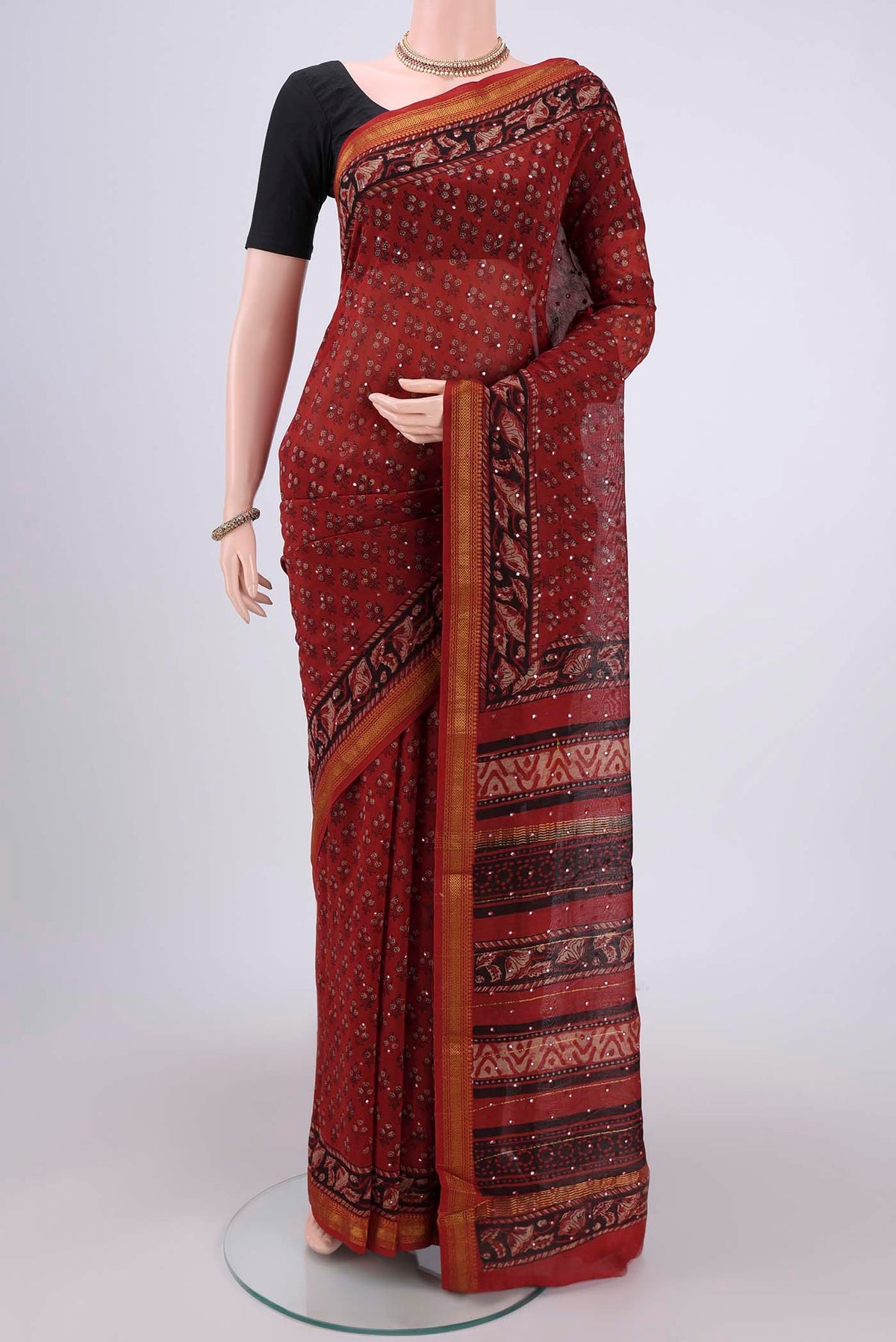 Rust Maheshwari Silk Cotton Saree with Printed design on the body and Zari Border.  displayed on a mannequin