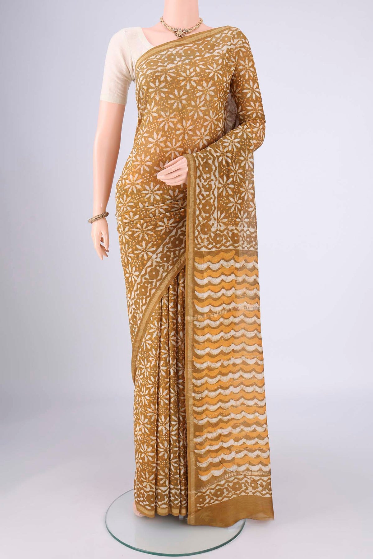 Mustard Maheshwari Silk Cotton Saree with Batik Print on the body and Zari Border.  displayed on a mannequin