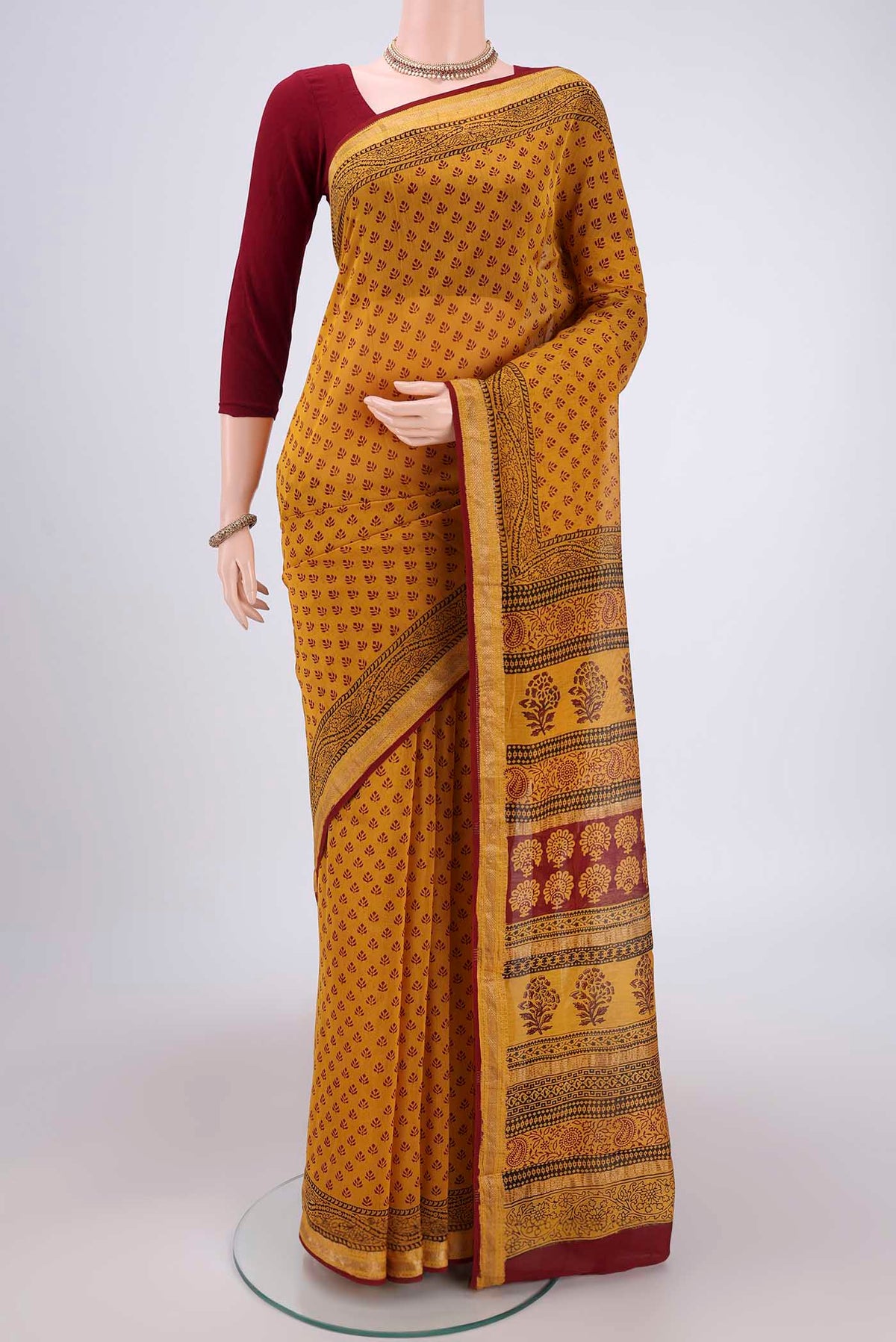 Mustard Maheshwari Silk Cotton Saree with Printed design on the body and Zari Border.  displayed on a mannequin