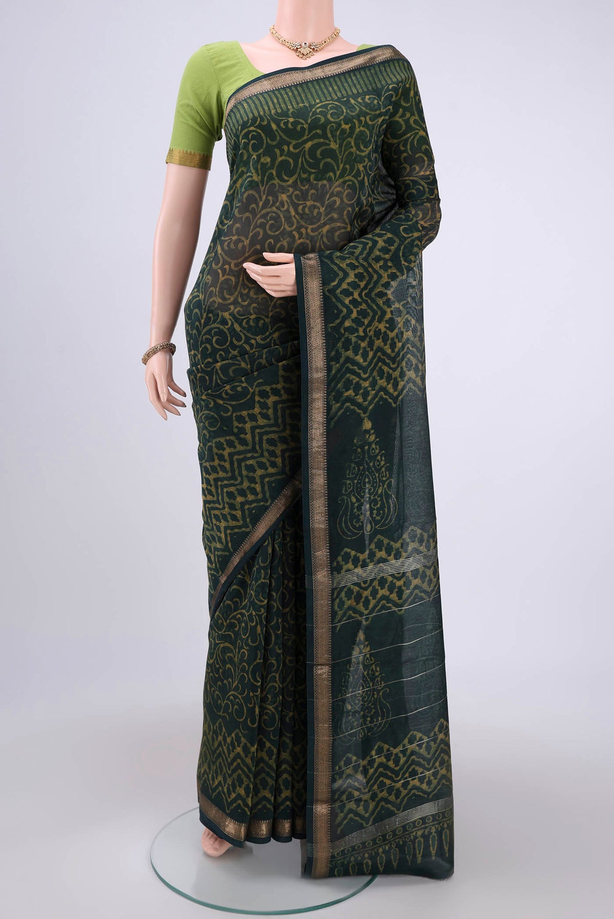 Bottle Green Maheshwari Silk Cotton Saree with Batik Print on the body and Zari Border.  displayed on a mannequin