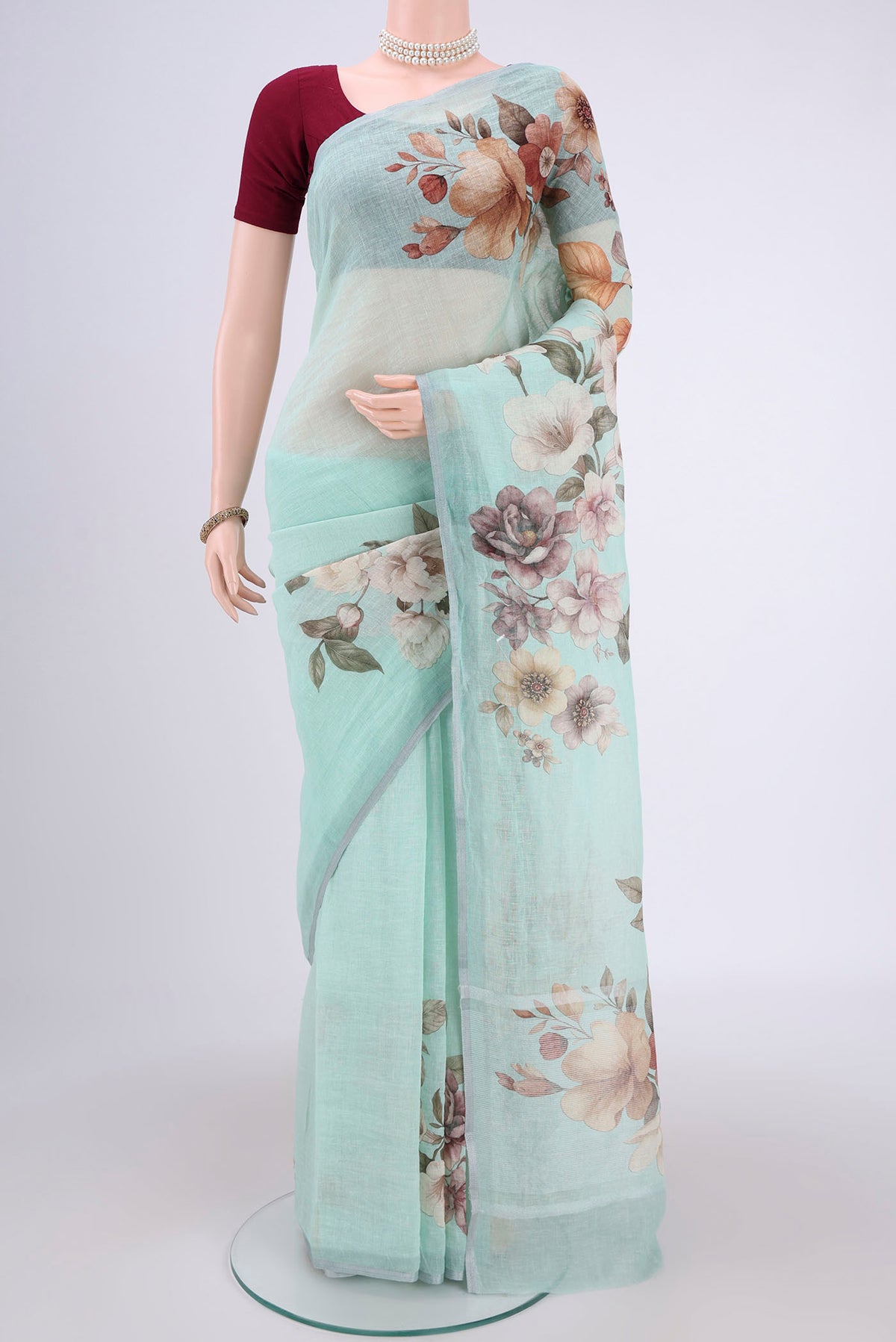 Sea Green Linen Saree with Floral Print on the body and Zari Border.  displayed on a mannequin
