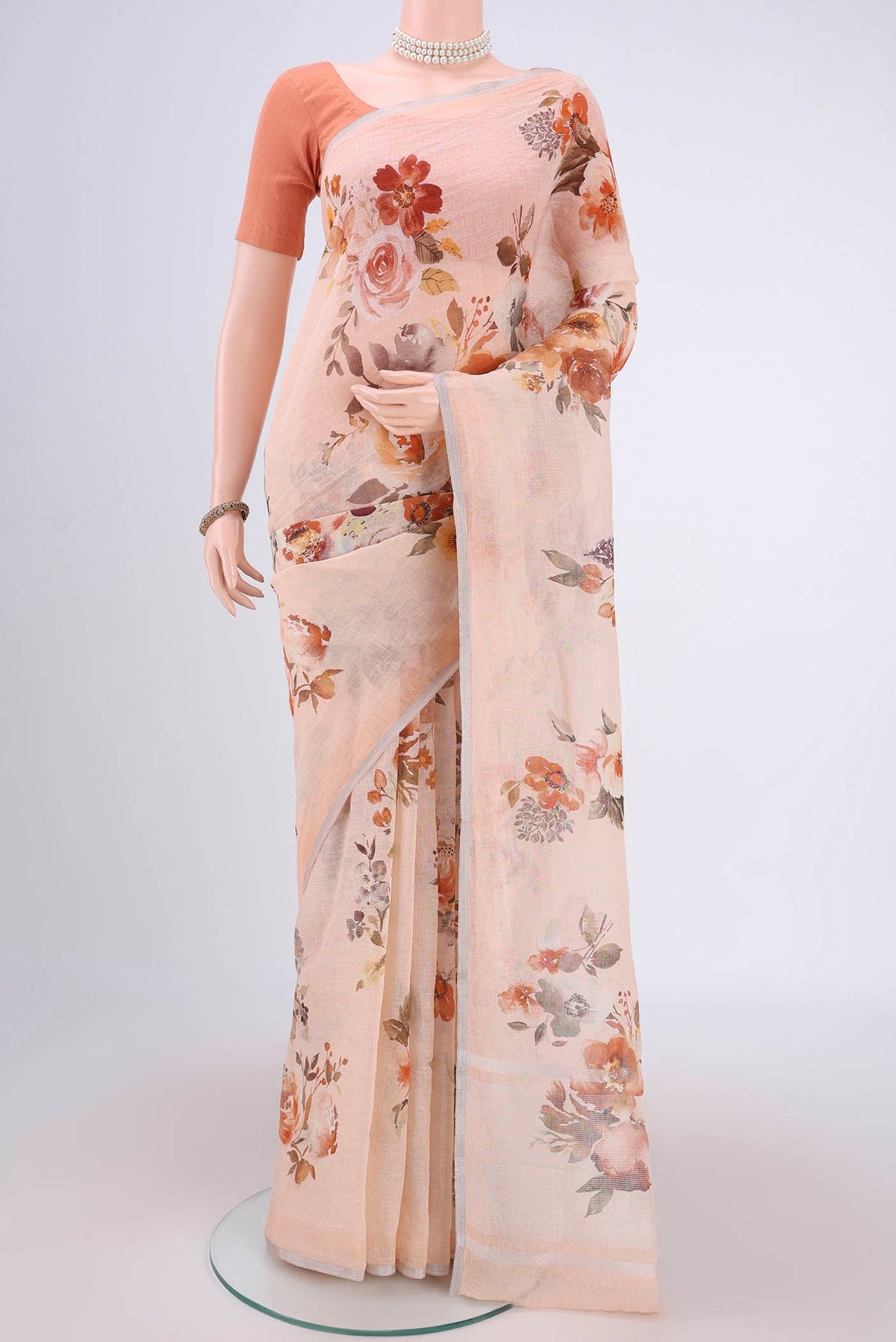 Peach Linen Saree with Floral Print on the body and Zari Border.  displayed on a mannequin