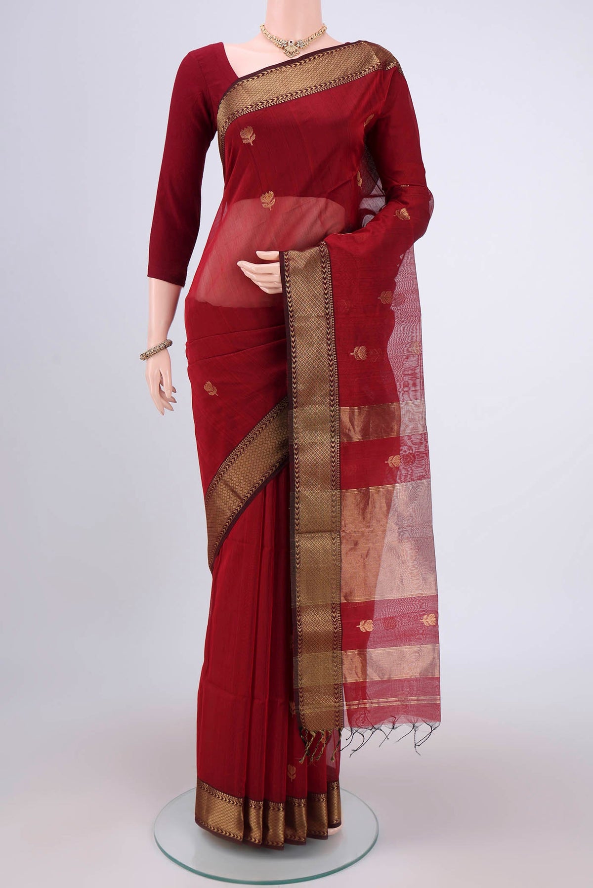 Maroon Maheshwari Silk Cotton Saree with Zari Butta on the body and Zari Border.  displayed on a mannequin