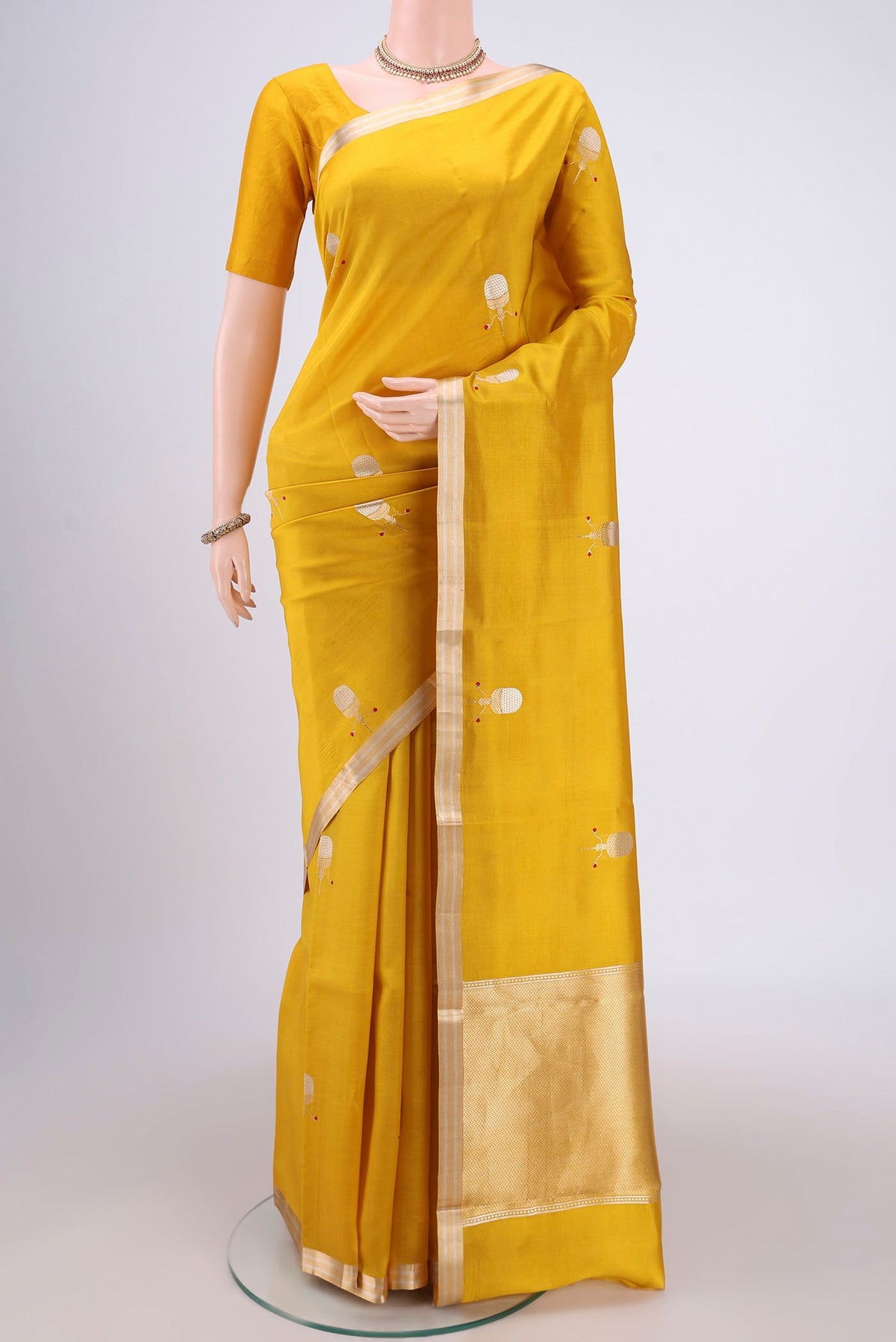 Mustard Banarasi Katan Silk Saree with Zari Butta on the body and Zari Border.  displayed on a mannequin