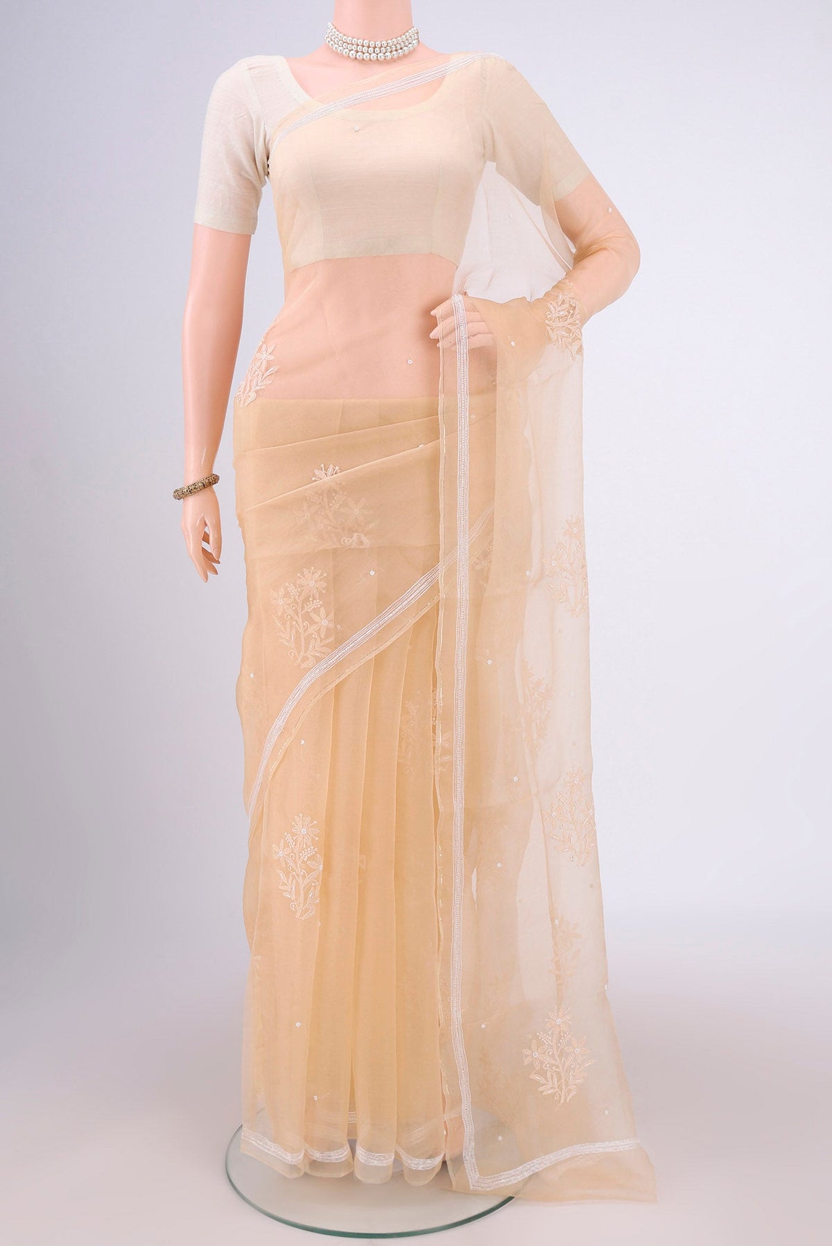 Beige Organza Silk Saree with Embroidery on the body and Thin Zari Line.  displayed on a mannequin