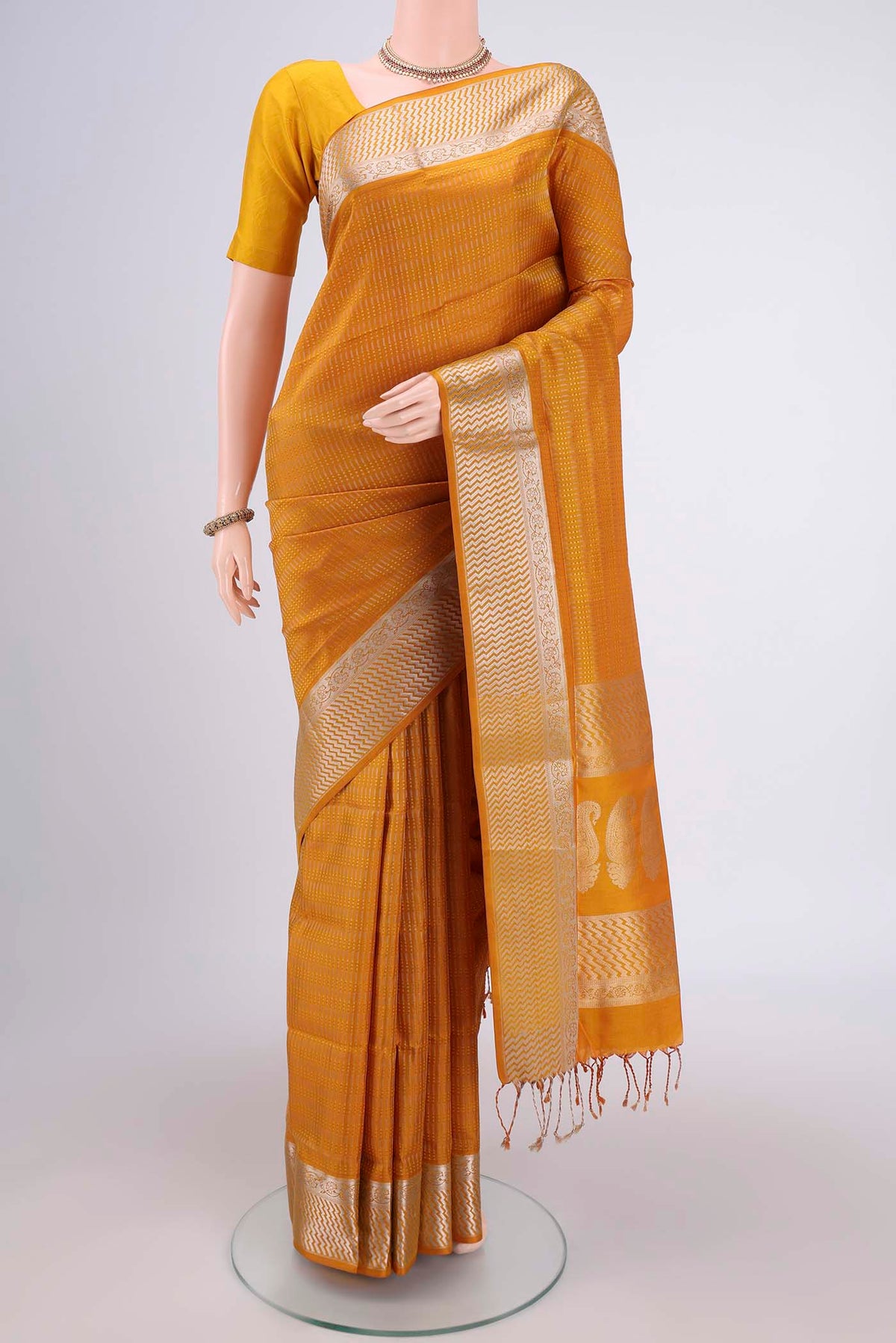 Mustard Soft Silk Saree with Jacquard design on the body and Zari Border.  displayed on a mannequin