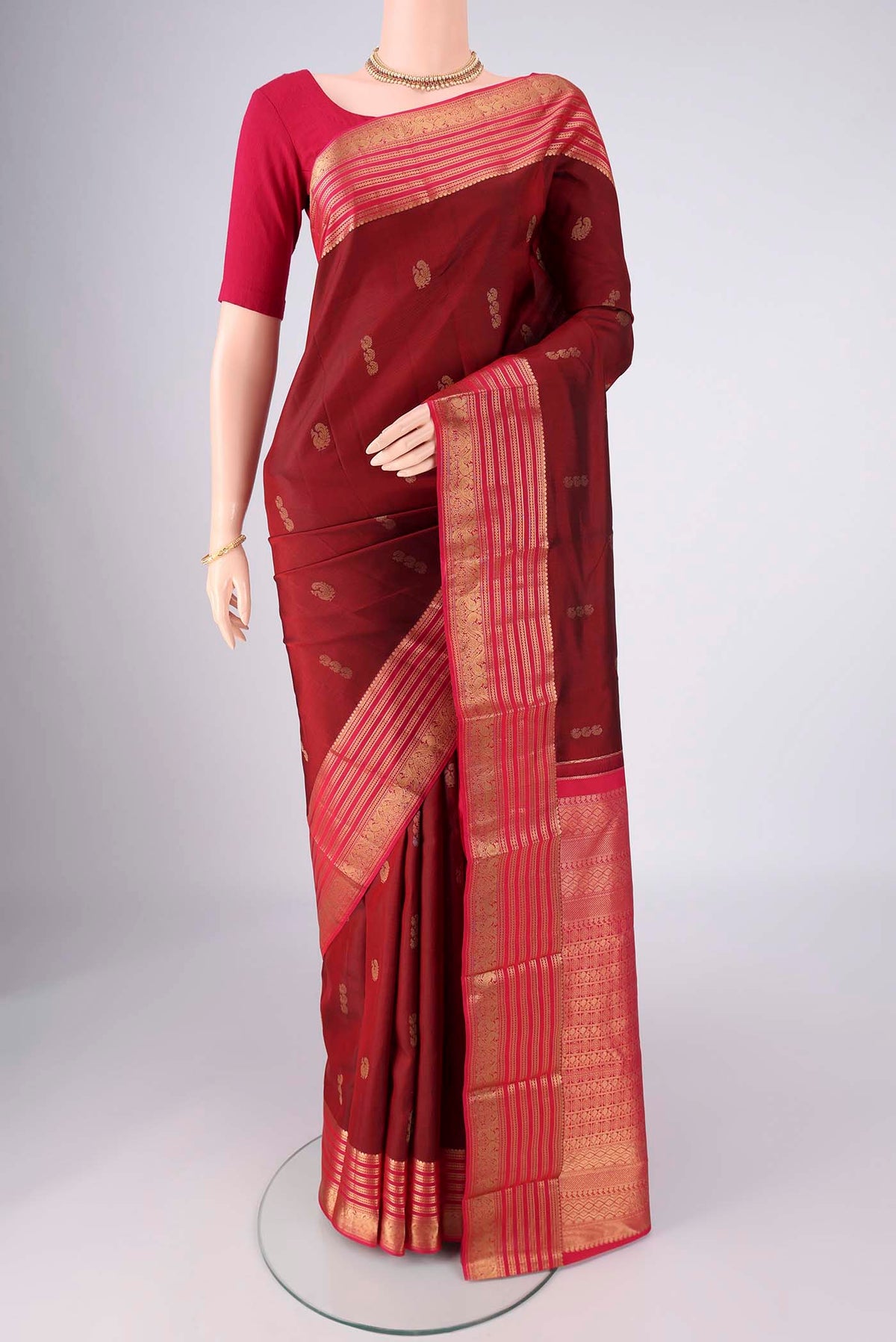Maroon Kanchipuram Silk Saree with Zari Butta on the body and Zari Border.  displayed on a mannequin