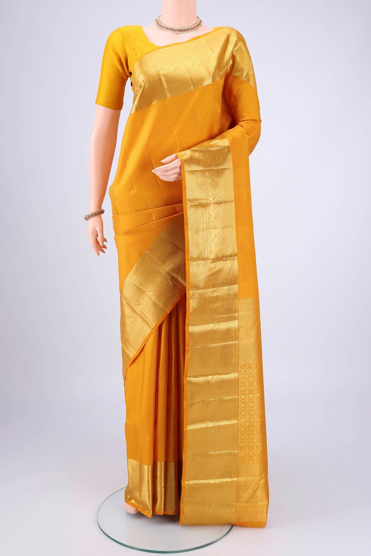 Mustard Kanjivaram Silk Saree with Jacquard design on the body and Zari Border.  displayed on a mannequin