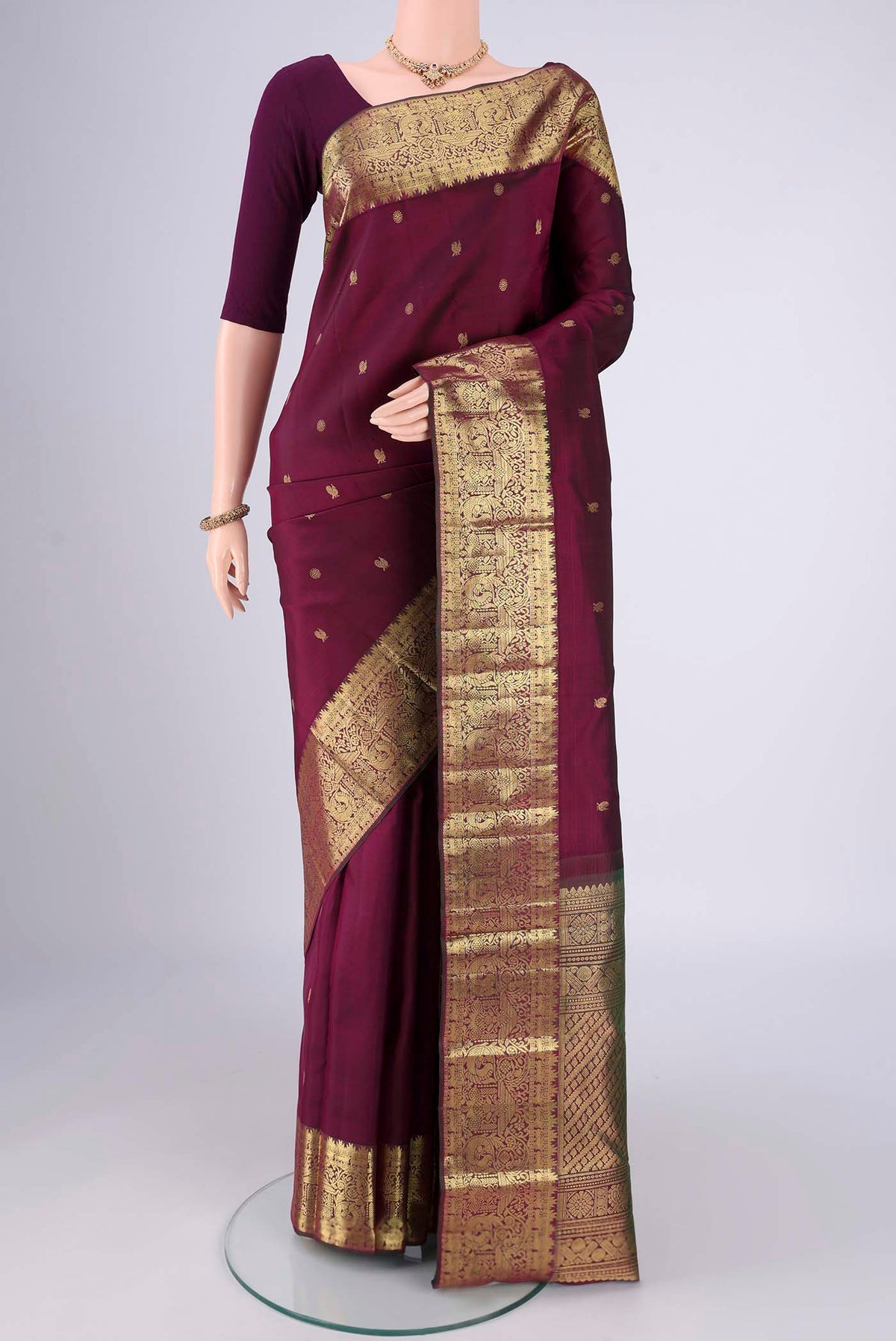 Pure Silk Pure Zari Maroon Kanchipuram Saree with Zari Butta on the body and Zari Border.  displayed on a mannequin