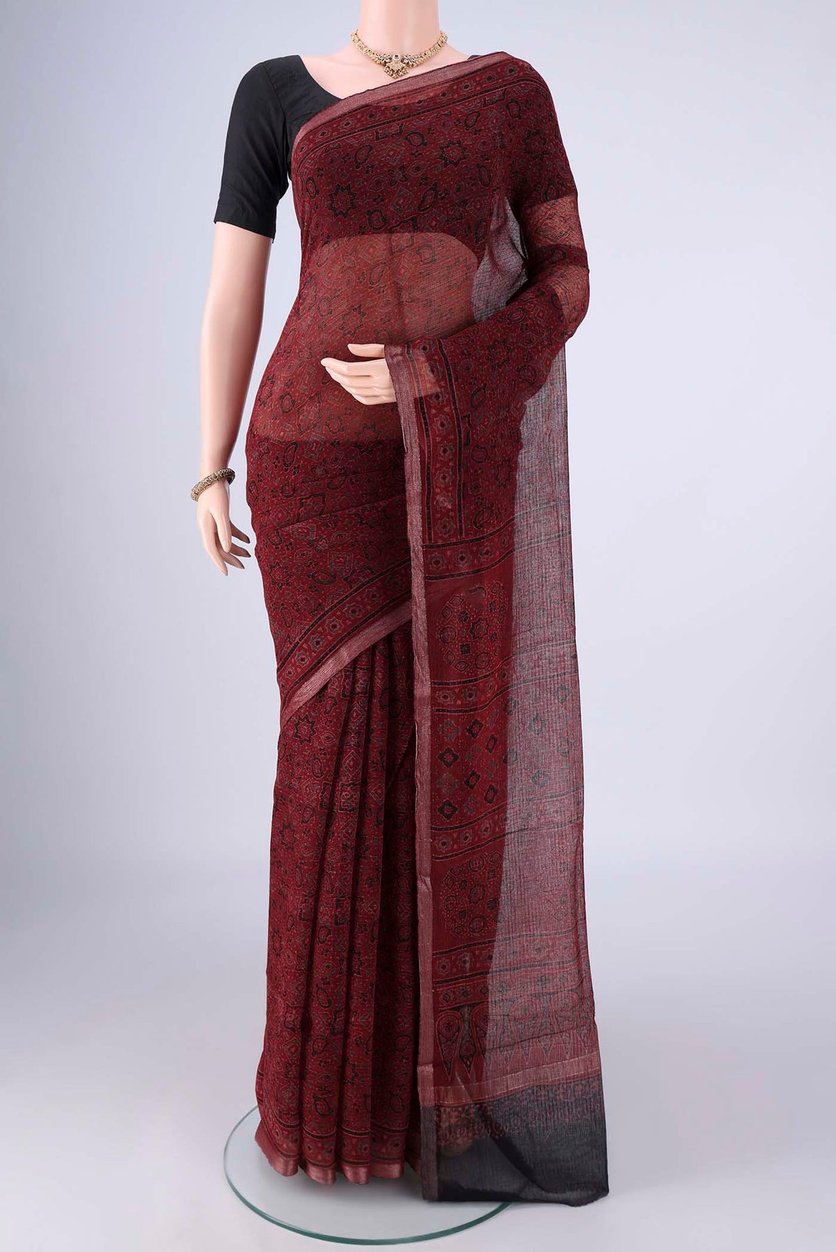 Maroon Kota Cotton Saree with Ajrakh Print on the body and Zari Border.  displayed on a mannequin