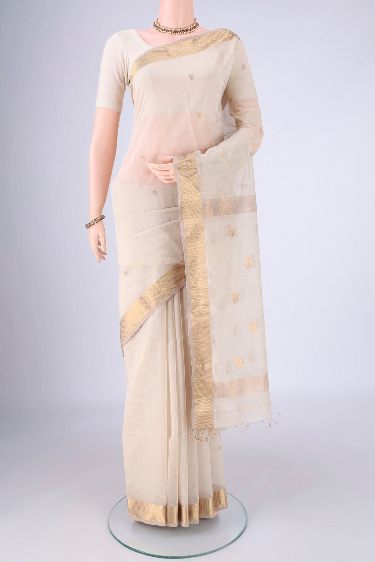 Cream Maheshwari Silk Cotton Saree with Zari Butta on the body and Zari Border.  displayed on a mannequin