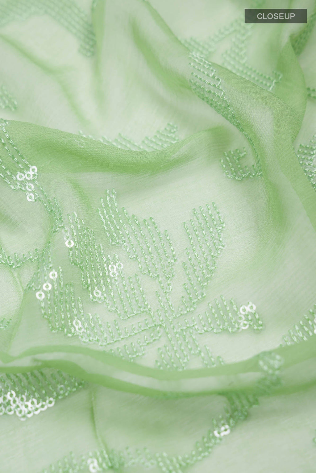 Close up of Green Blended Chiffon Saree with Embroidery on the body and Lace Border.  displaying folds