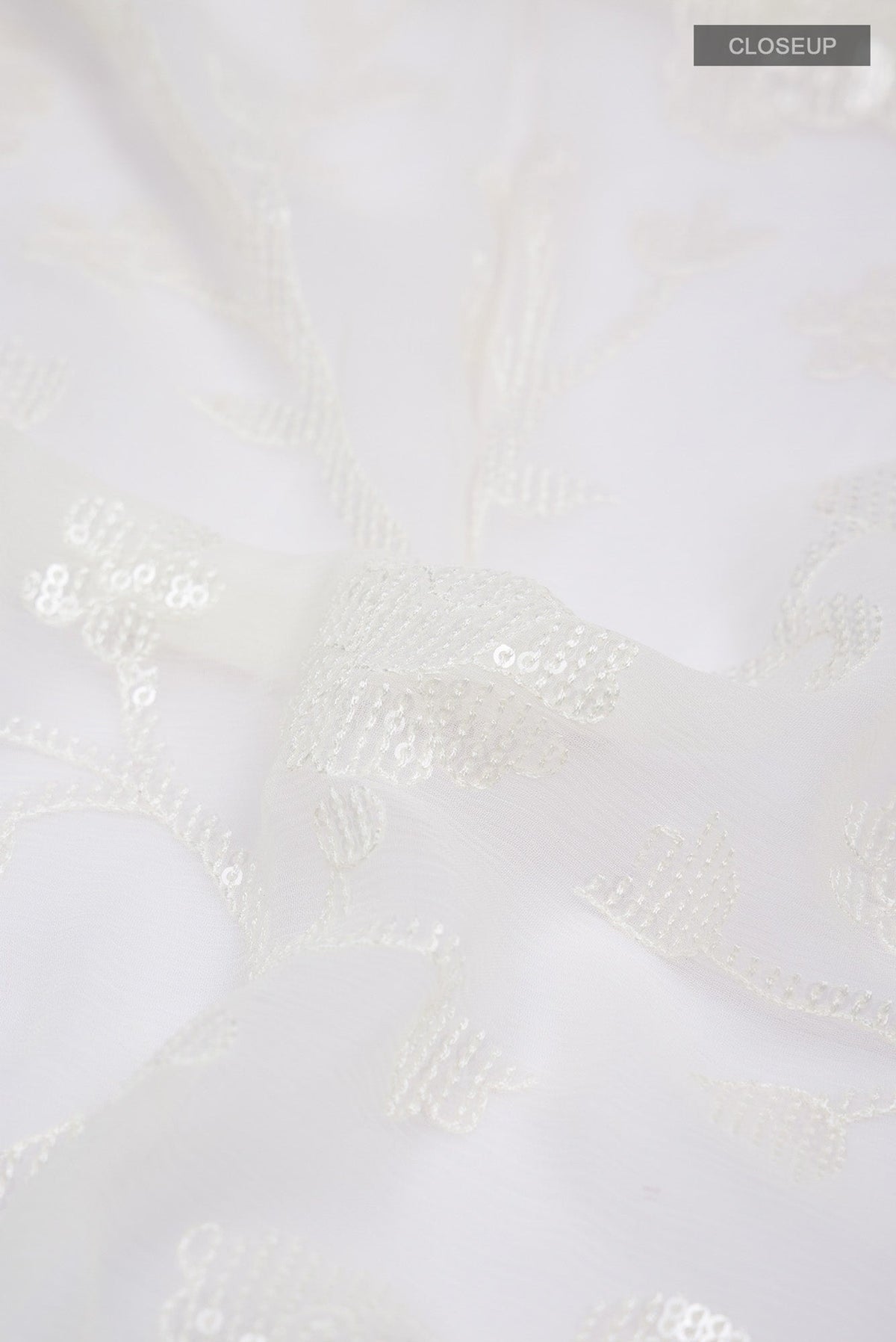 Close up of Cream Blended Chiffon Saree with Embroidery on the body and Lace Border.  displaying folds