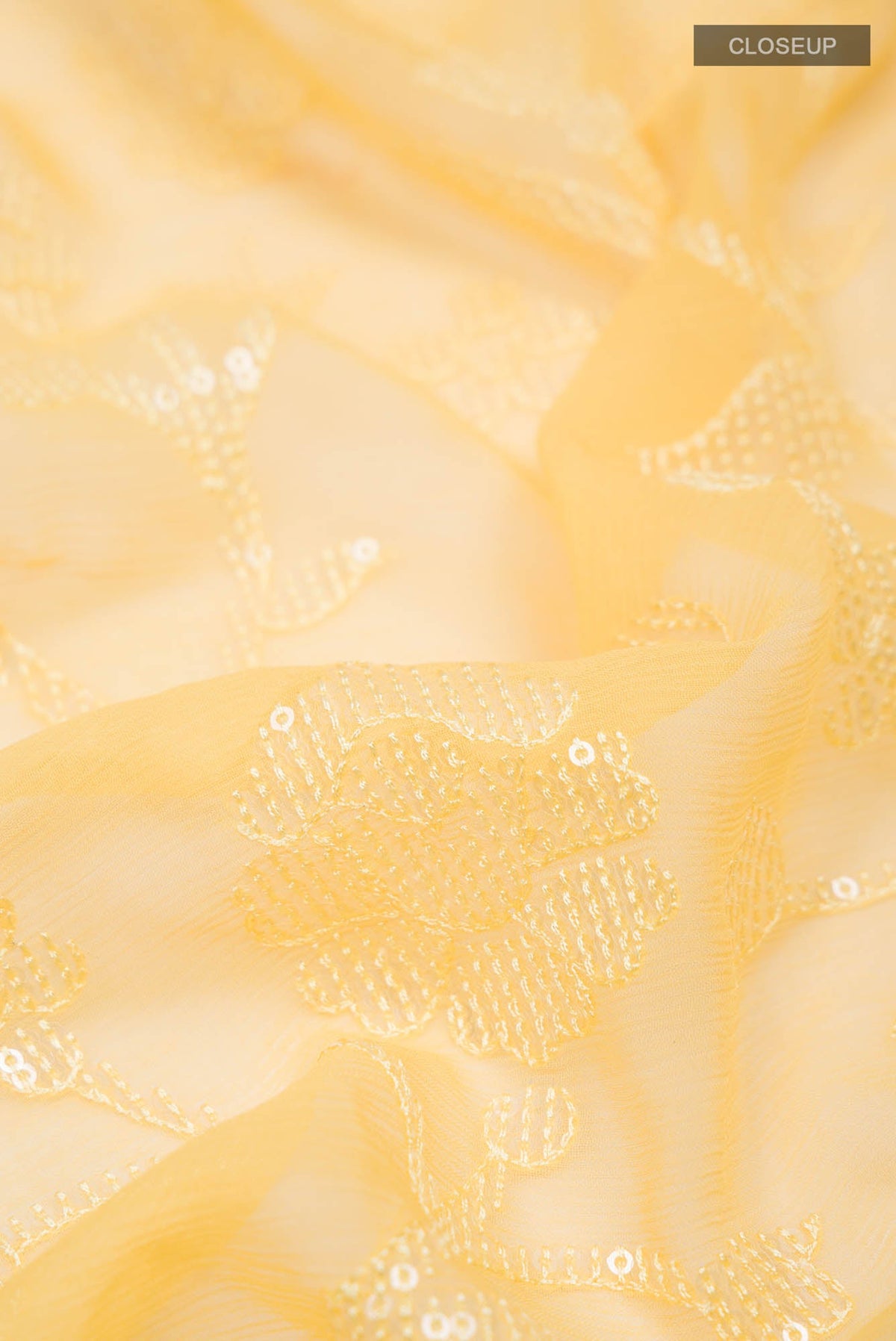 Close up of Yellow Blended Chiffon Saree with Embroidery on the body and Lace Border.  displaying folds