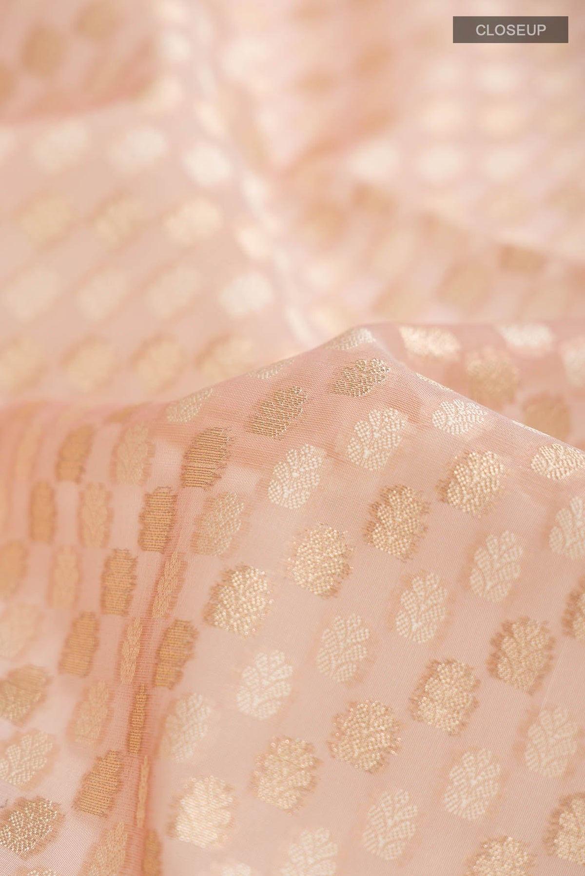 Close up of Rose Gold Blended Kora Cotton Saree with Zari And Thread Butta on the body and Zari Border.  displaying folds