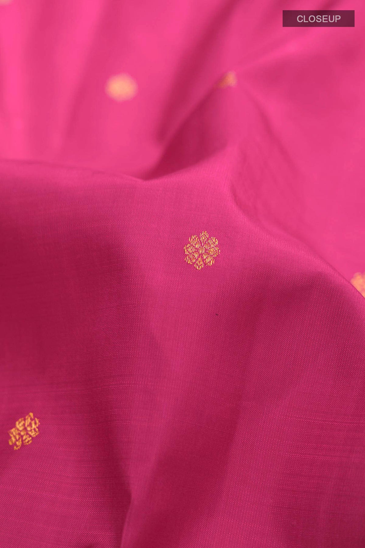Close up of Pink Kanchipuram Silk Saree with Zari Butta on the body and Zari Border displaying folds