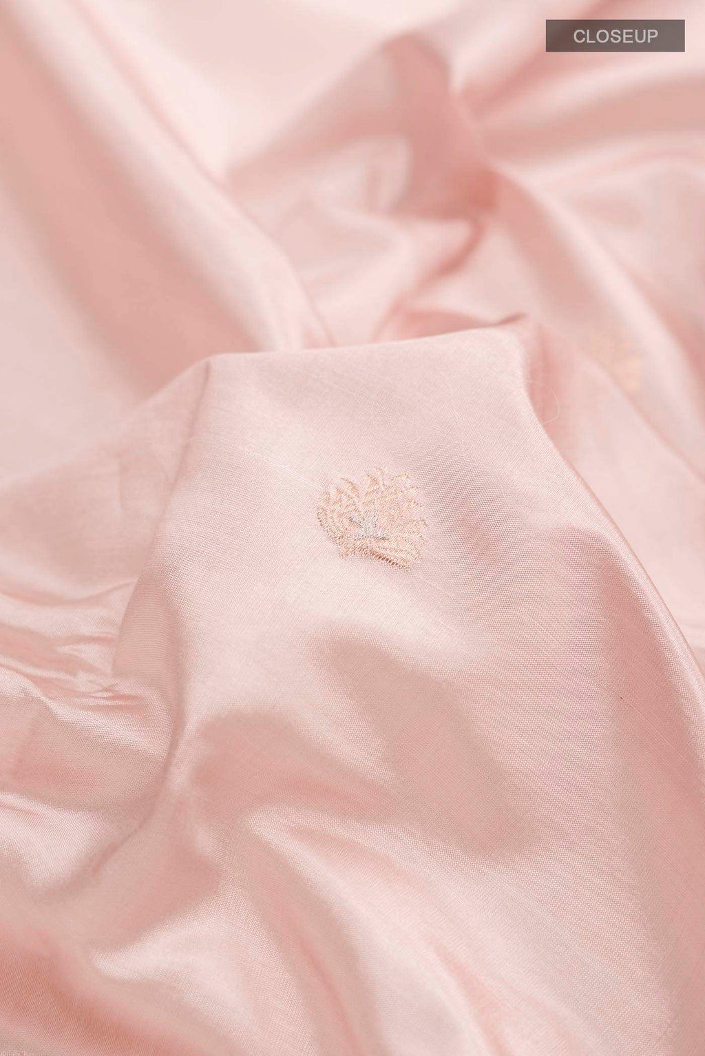 Close up of Rose Gold Banarasi Katan Silk Saree with Zari Butta on the body and Zari Border displaying folds