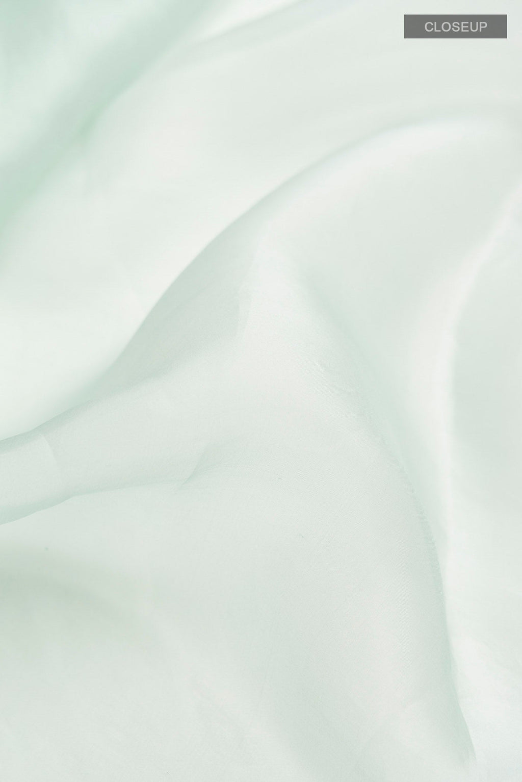 Close up of Green Organza Silk Saree with Plain Body and Embroidery Border displaying folds