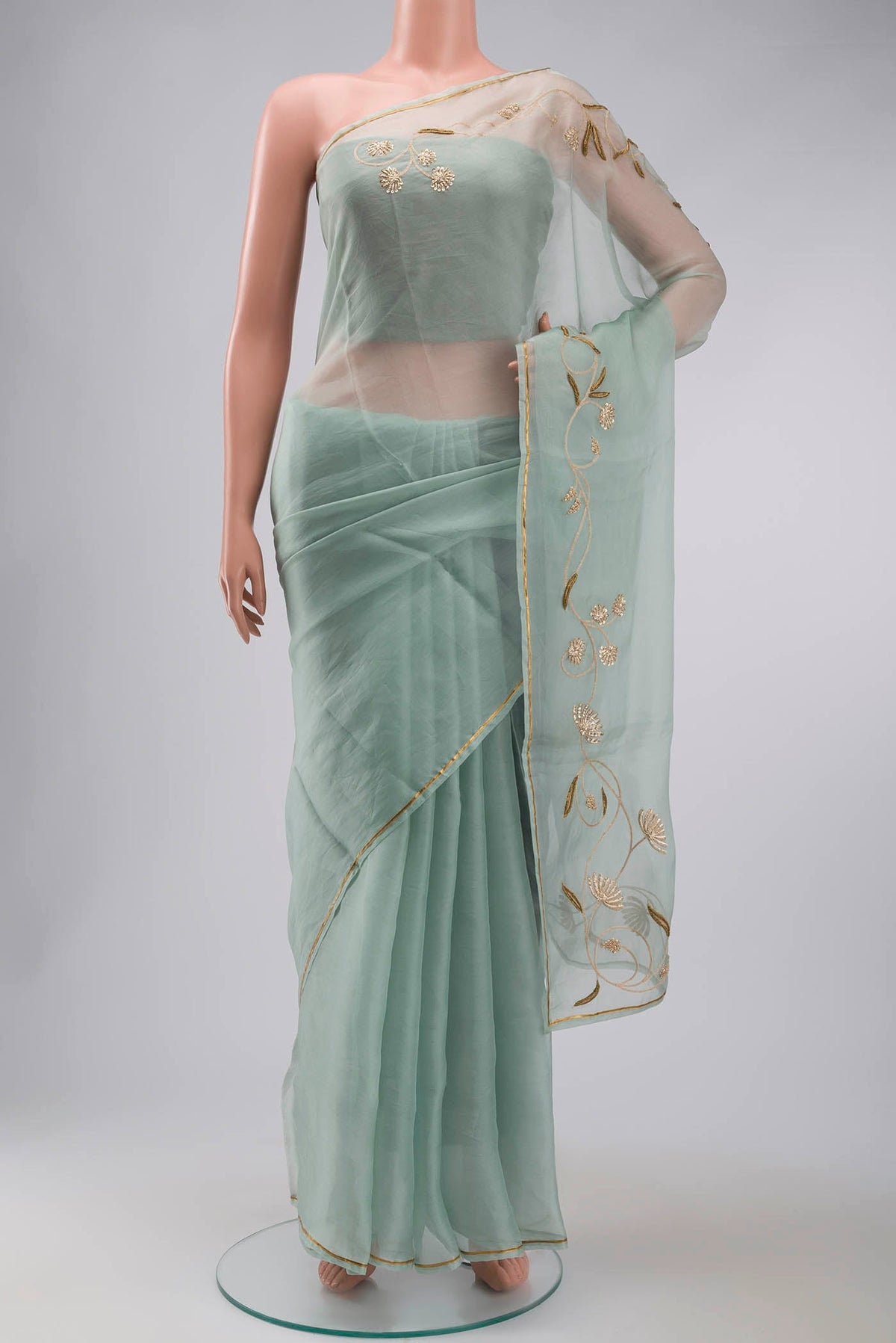 Green Organza Silk Saree with Plain Body and Embroidery Border displayed on a mannequin