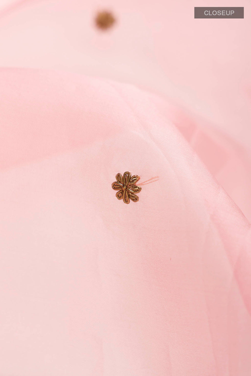 Close up of Pink Organza Silk Saree with Embroidery on the body and Zari Border displaying folds