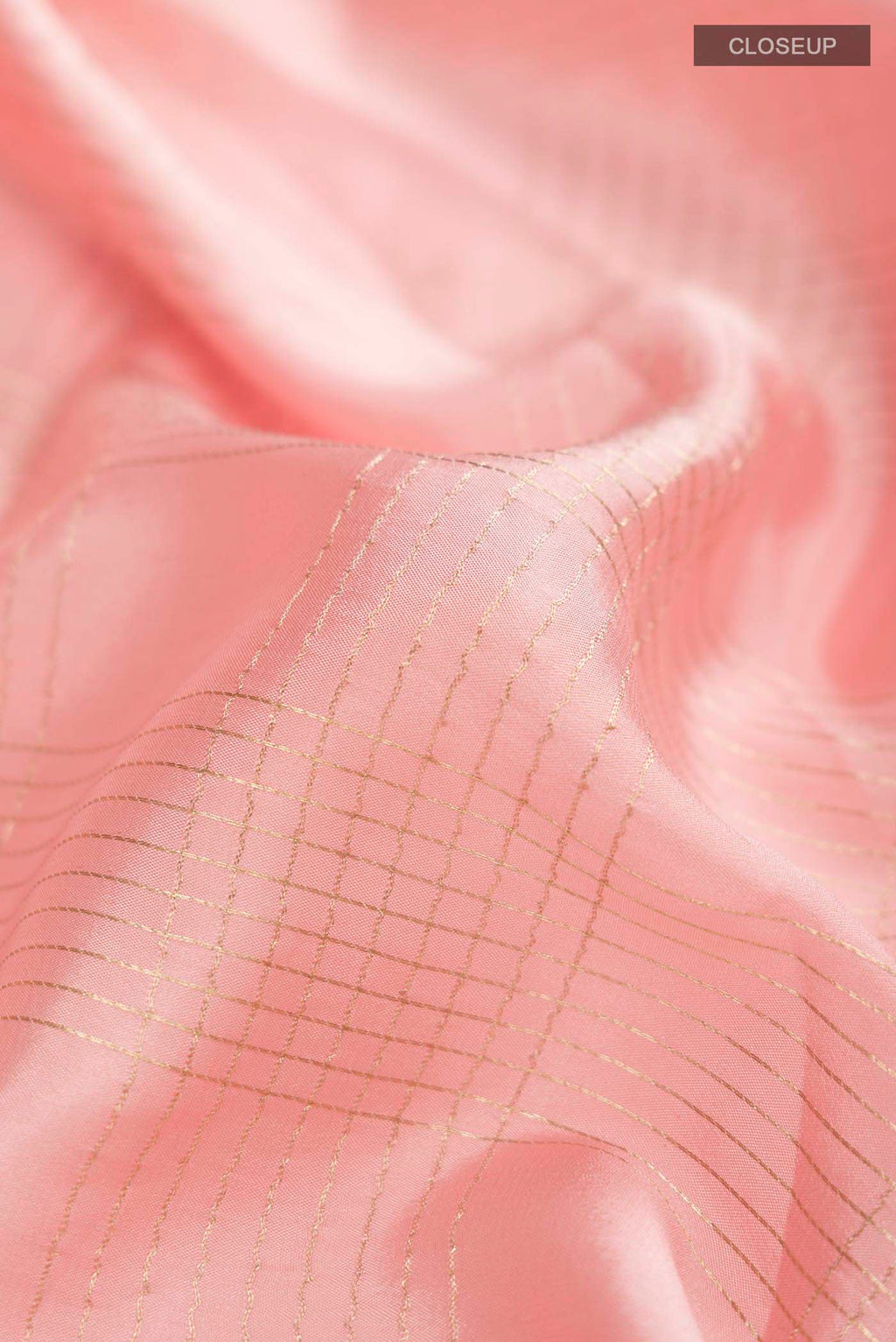 Close up of Peach Mysore Crepe Saree with Checked design on the body and Zari Border displaying folds