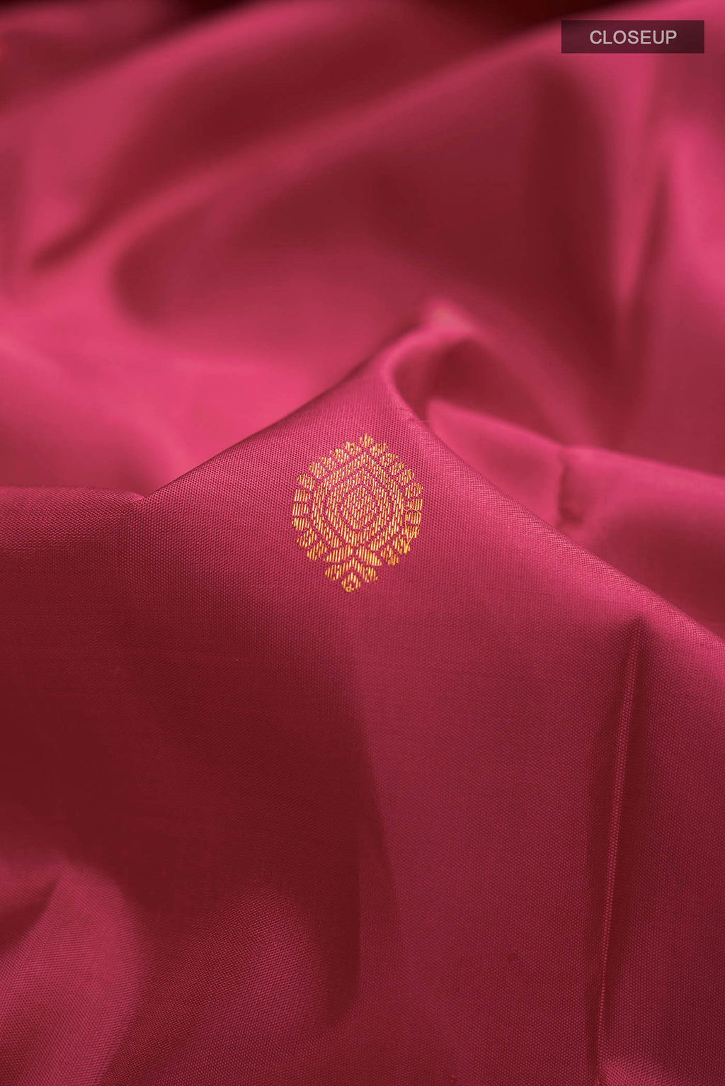 Close up of Magenta Kanchipuram Silk Saree with Zari Butta on the body and Zari Border displaying folds