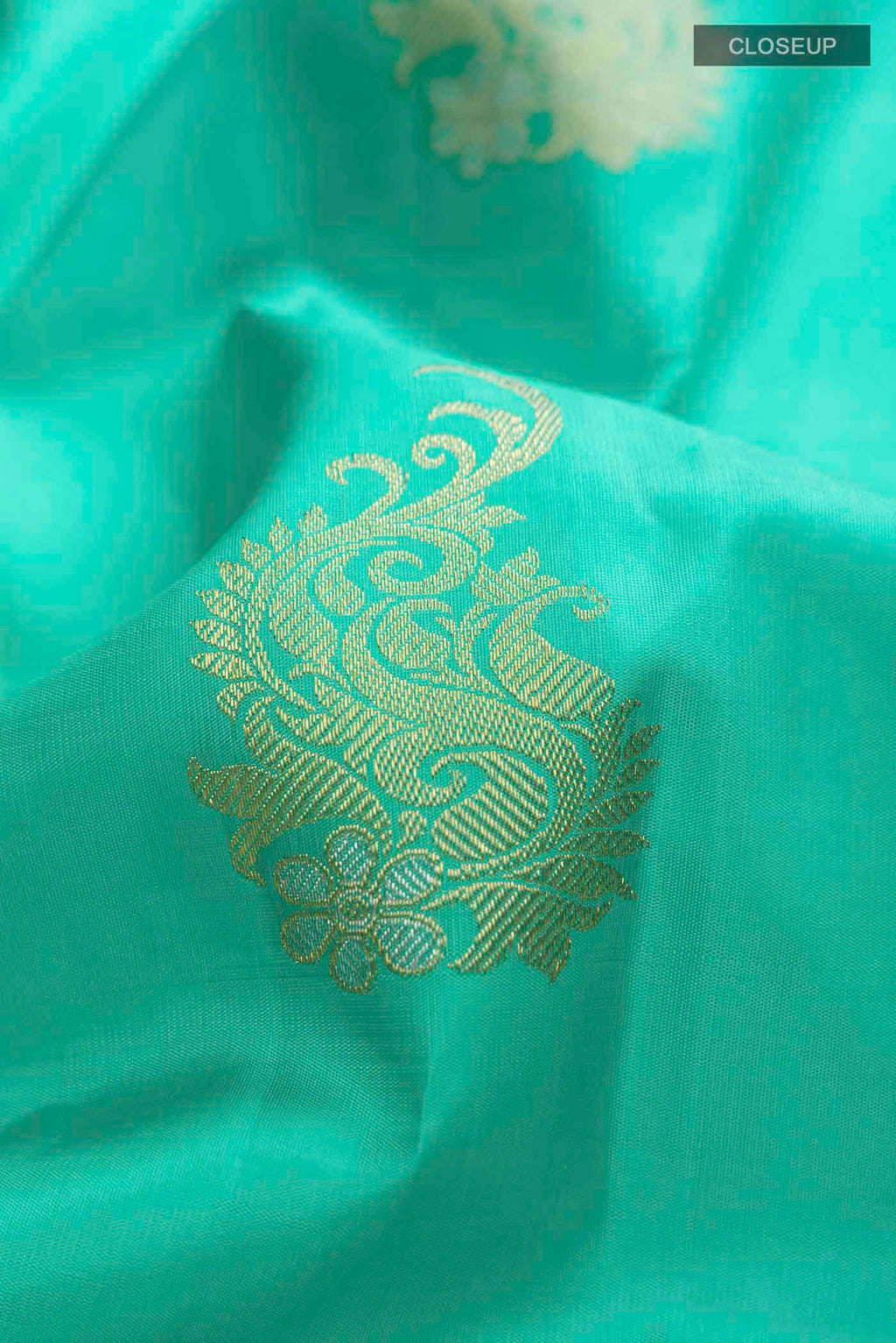 Close up of Green Kanchipuram Silk Saree with Zari Butta on the body and Zari Border displaying folds