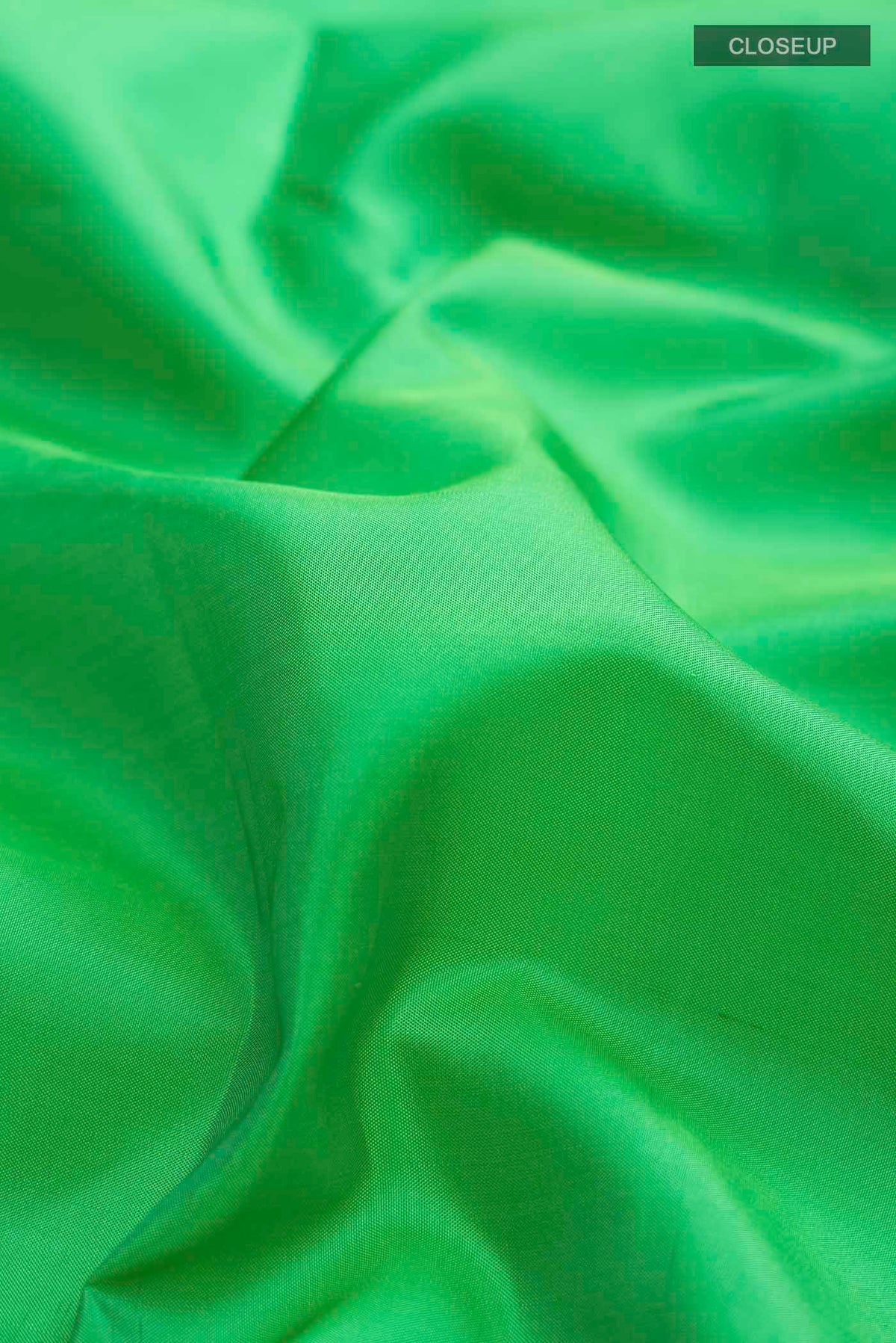Close up of Green Soft Silk Saree with Plain Body and Zari Border displaying folds