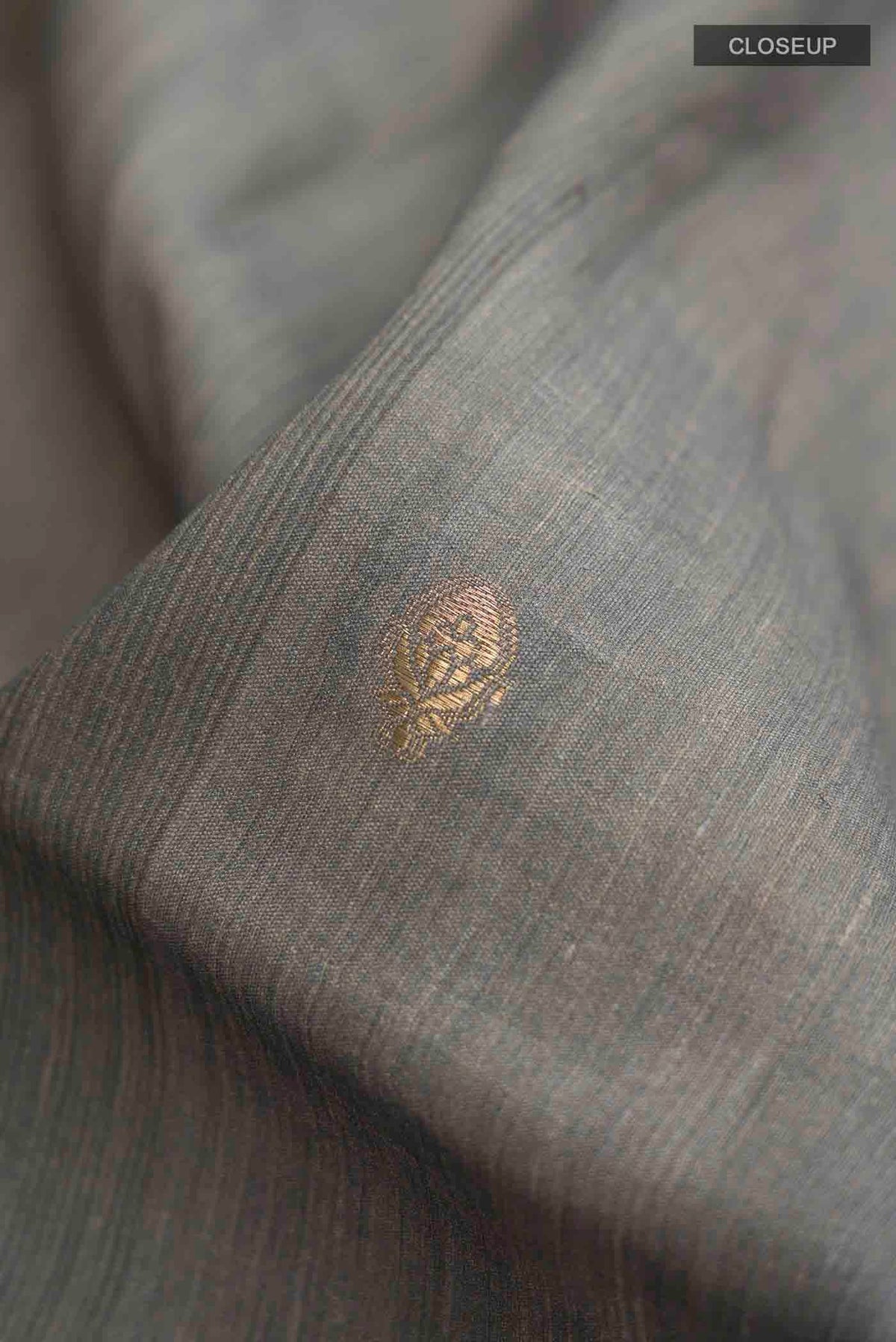 Close up of Grey Tussar Silk Saree with Zari Butta on the body and Printed Border displaying folds