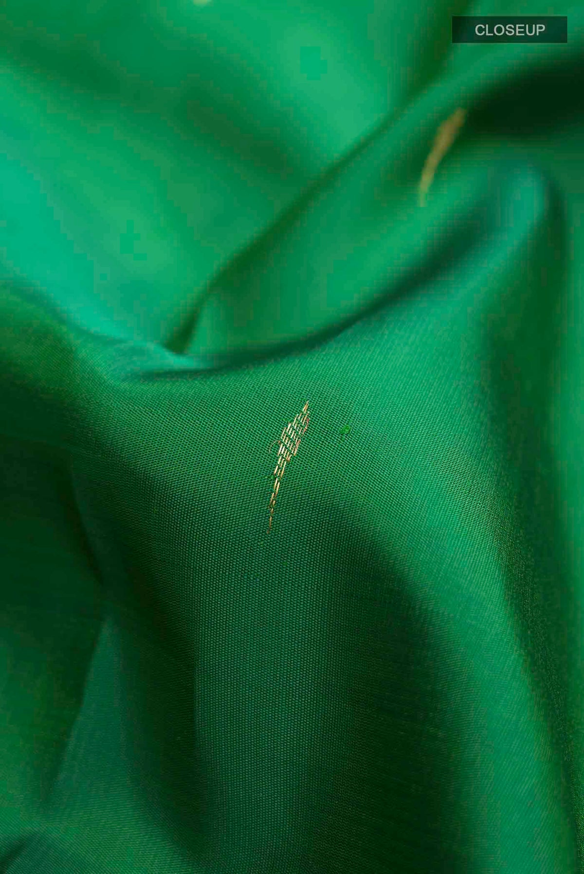 Close up of Green Kanchipuram Silk Saree with Zari Butta on the body and Zari Border displaying folds