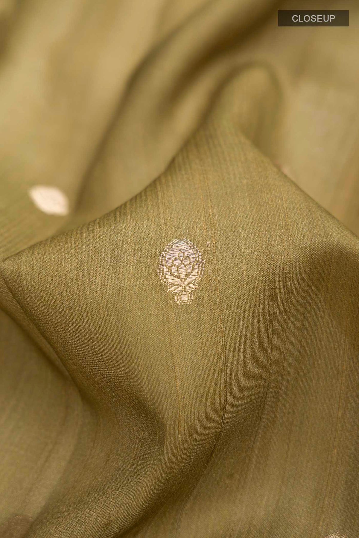 Close up of Green Tussar Silk Saree with Zari Butta on the body and Printed Border displaying folds