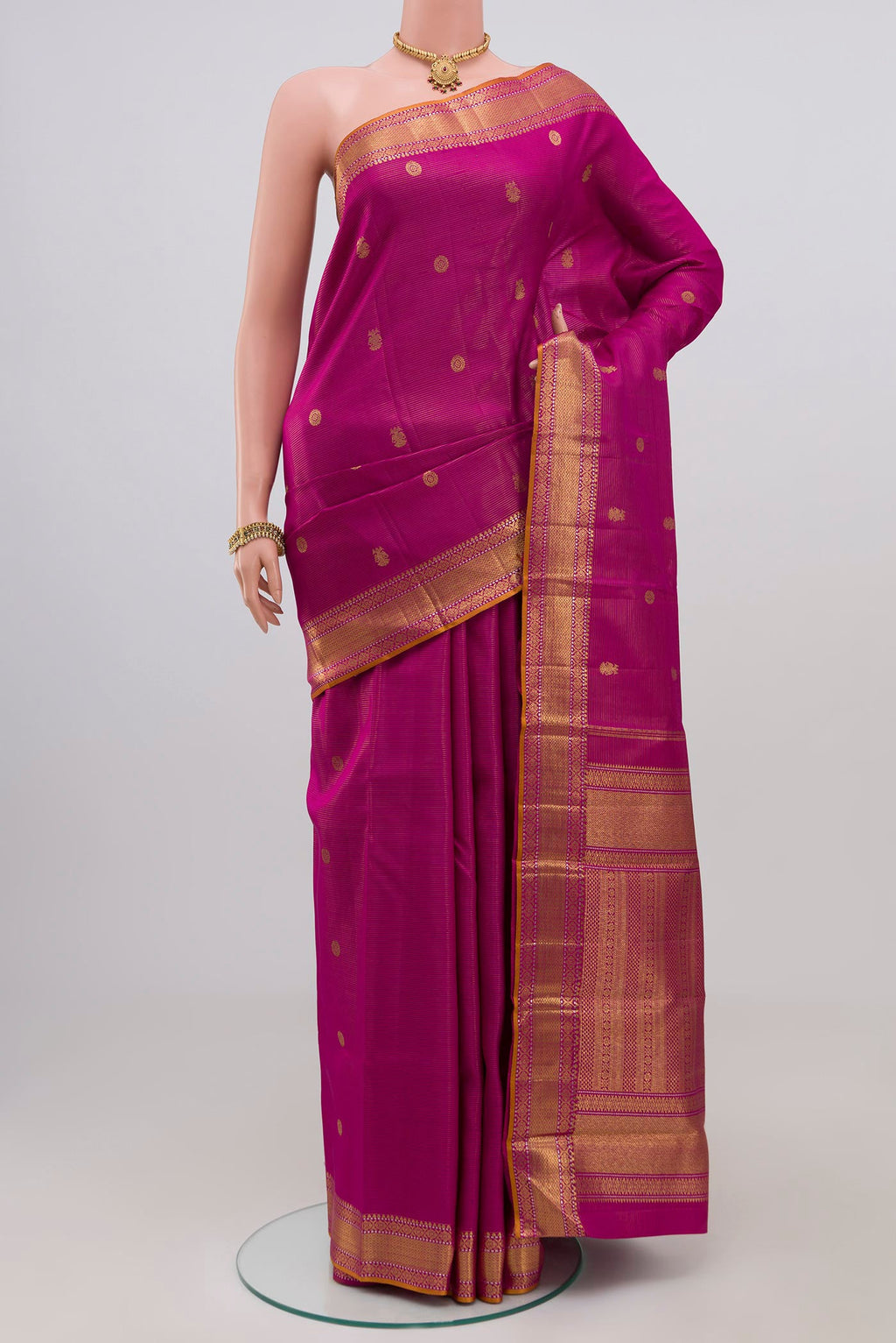 Magenta Kanjivaram Silk Saree with Zari Butta on the body and Zari Border.  displayed on a mannequin