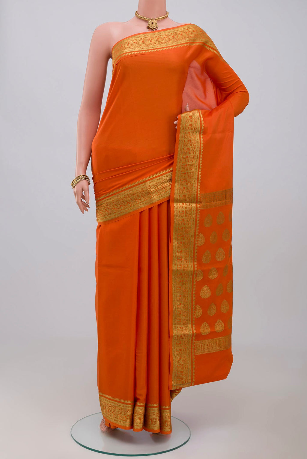 Orange Crepe Saree with Plain Body and Zari Border.  displayed on a mannequin
