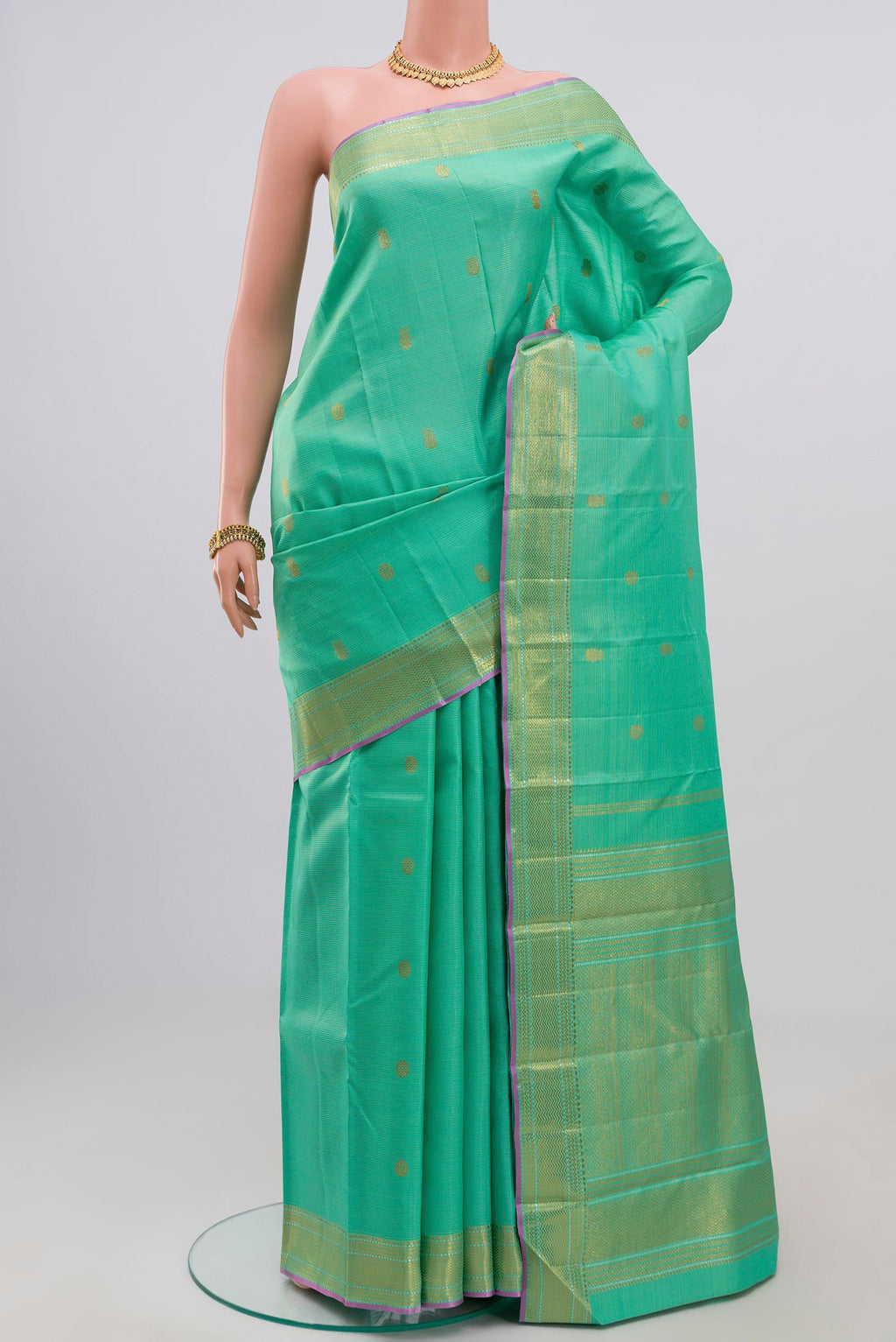 Green Kanjivaram Saree with Zari Butta on the body and Zari Border.  displayed on a mannequin