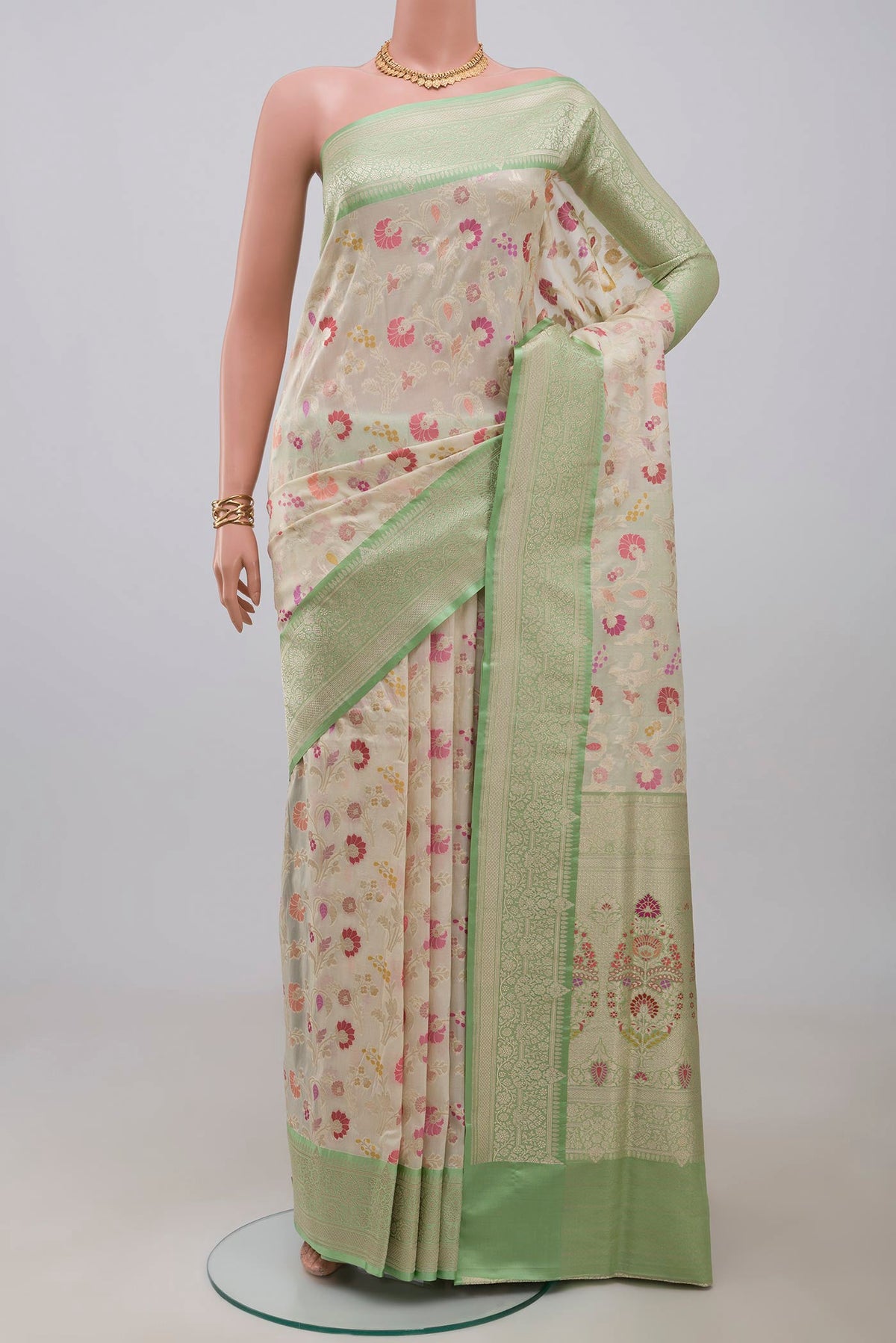 Cream Banarasi Silk Saree with Zari And Thread Butta on the body and Zari Border.  displayed on a mannequin