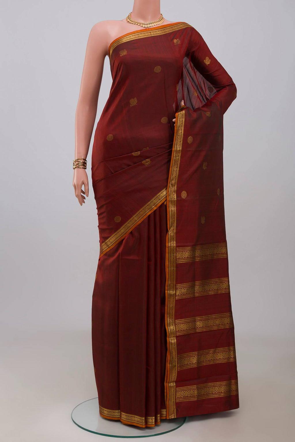 Maroon Kanchipuram Silk Saree with Zari Butta on the body and Zari Border.  displayed on a mannequin