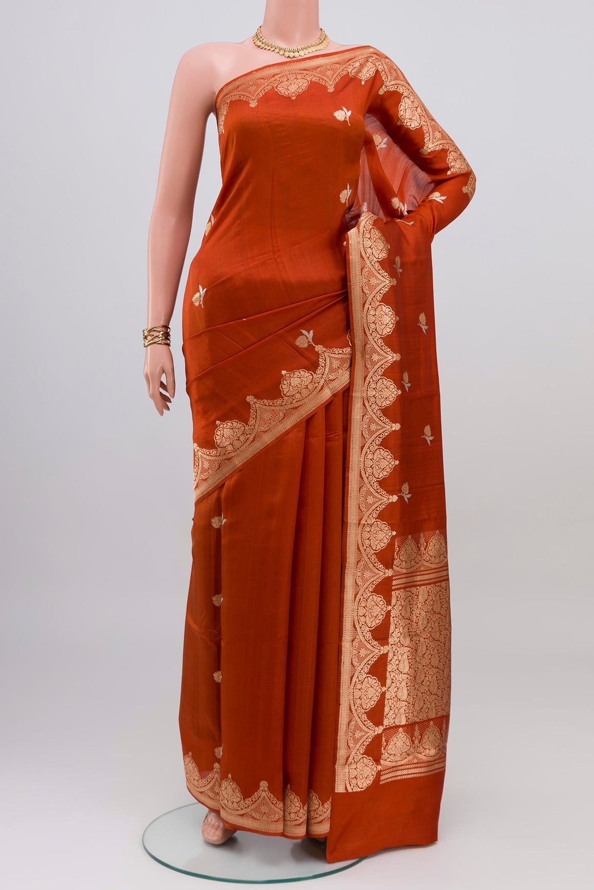 Rust Banarasi Katan Silk Saree with Zari Butta on the body and Fancy Border.  displayed on a mannequin