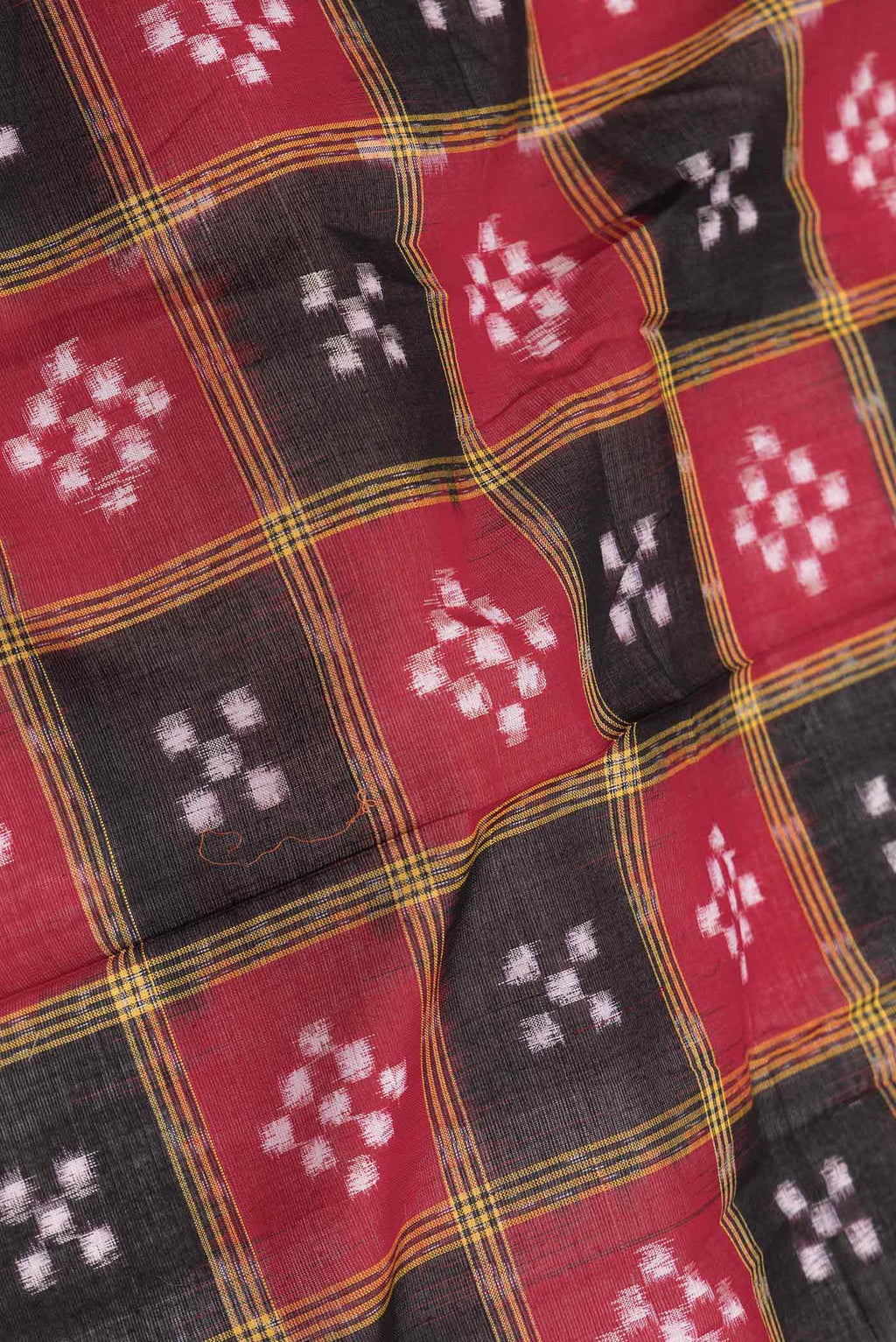 Close up of Red and Black Color Double Ikat Saree with Ikat Print on the body and Thread Border displaying folds
