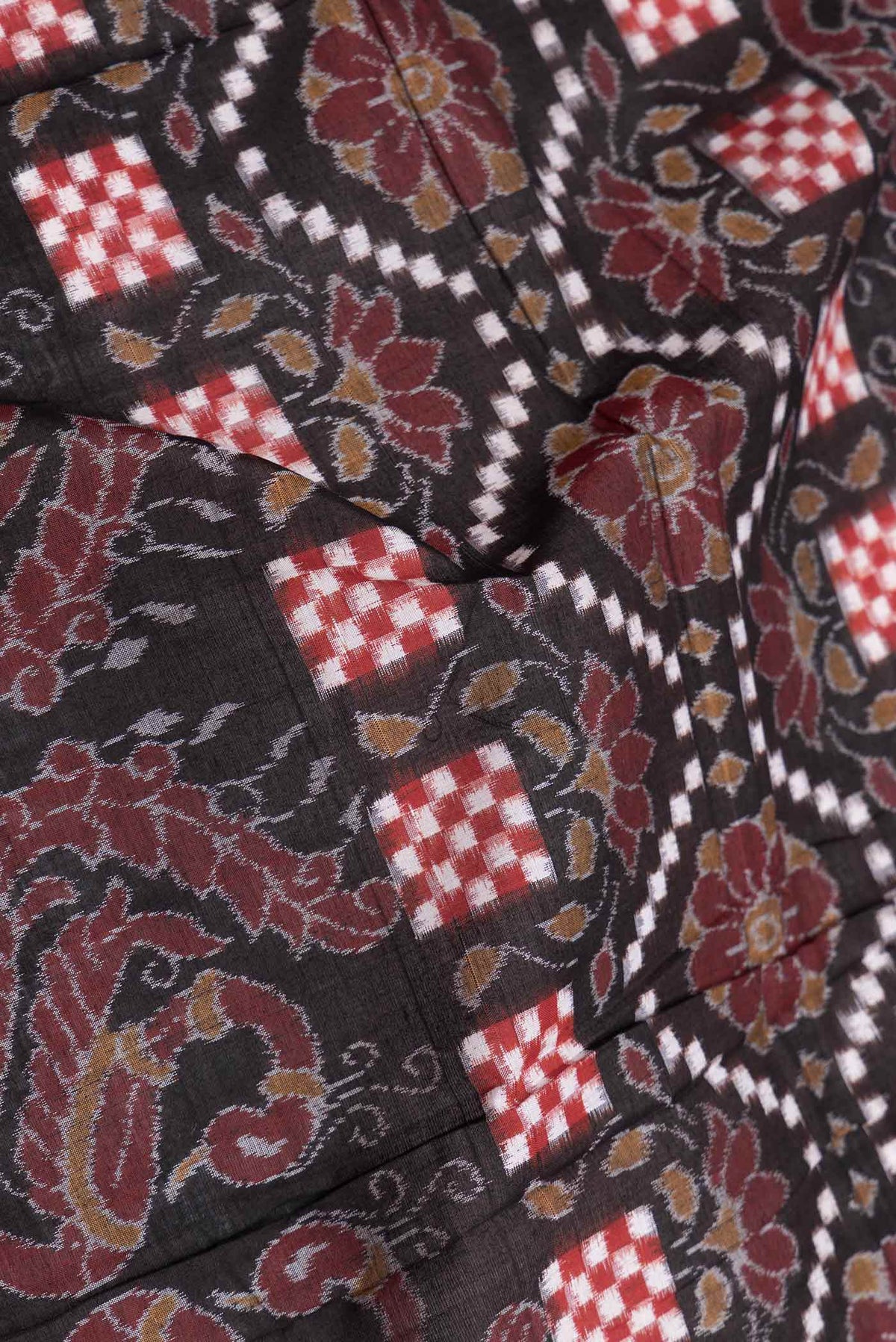 Close up of Black Dual Tone Double Ikat Saree with Ikat Print on the body and Thread Border displaying folds