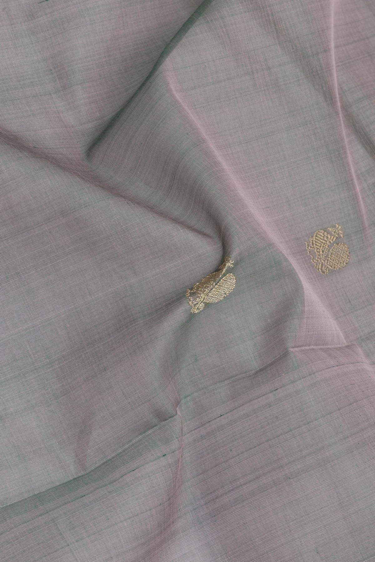 Close up of Grey with Green Color Silk Cotton Saree with Zari Butta on the body and Zari Border.  displaying folds