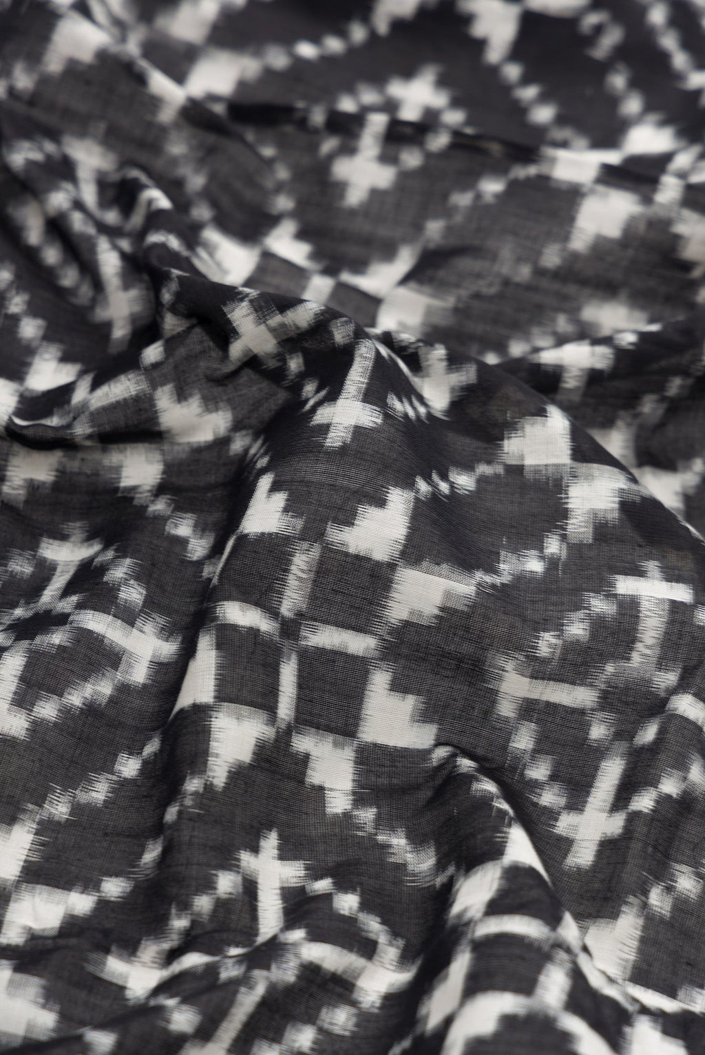 Close up of Black Dual Tone Double Ikat Saree with Ikat Print on the body and Plain Border.  displaying folds