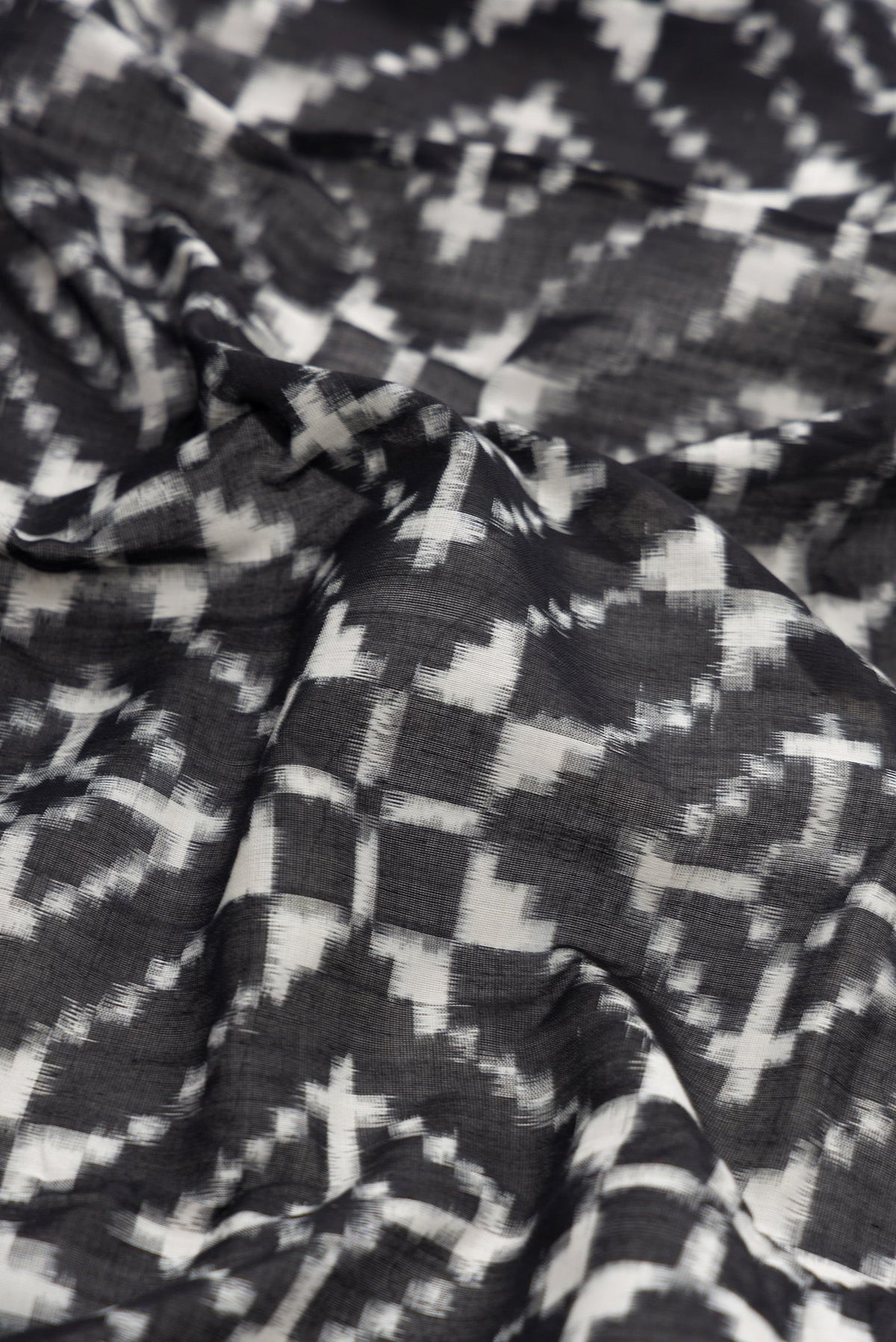 Close up of Black Dual Tone Double Ikat Saree with Ikat Print on the body and Plain Border.  displaying folds