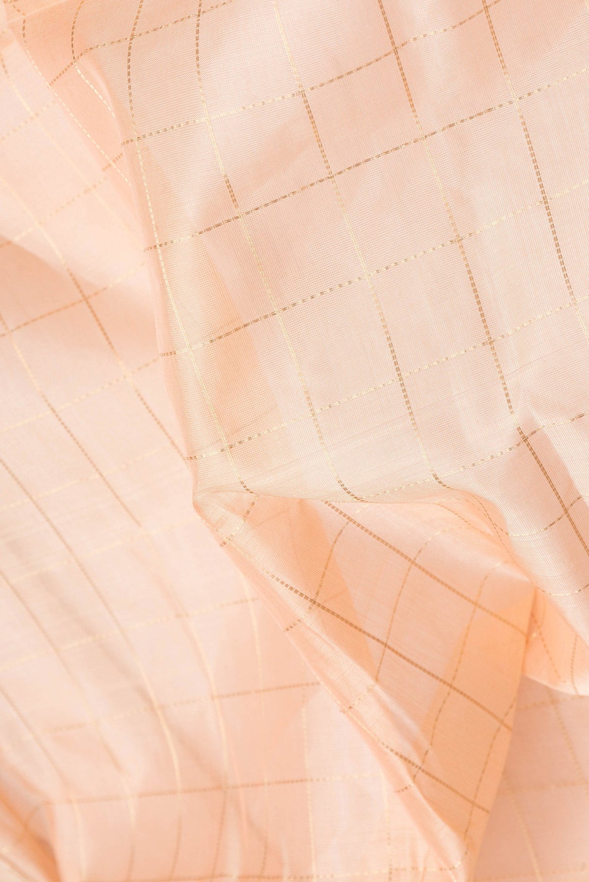 Close up of Golden Peach Dual Tone Silk Cotton Saree with Checked design on the body and Zari Border.  displaying folds