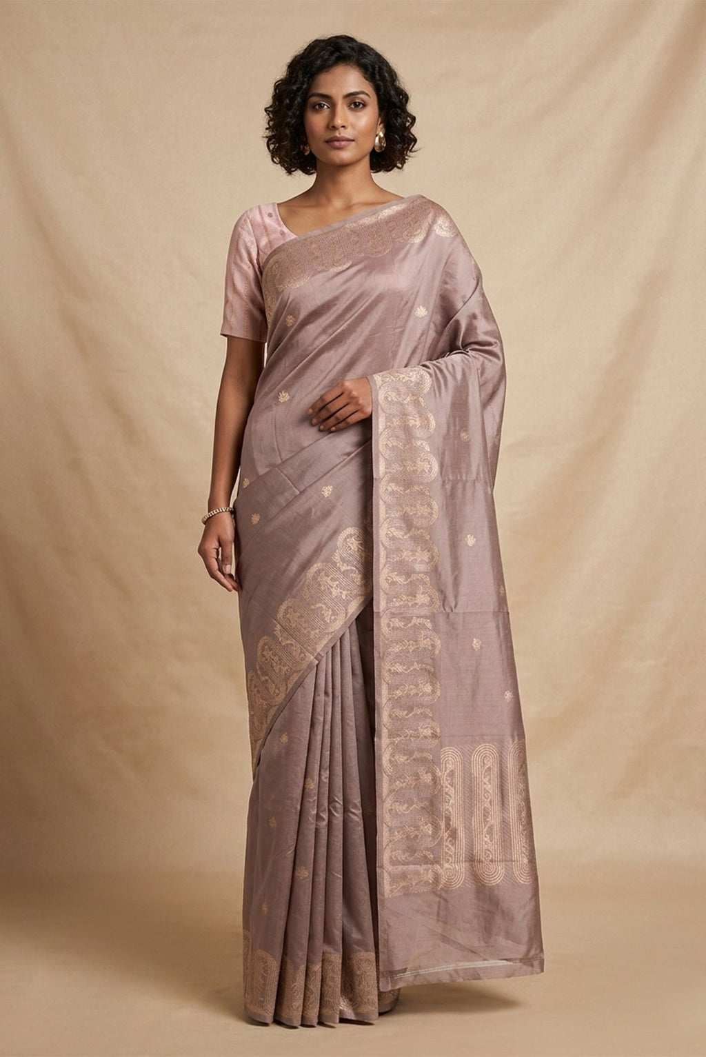Model wearing a Mandhara, handwoven in Katan silk, brings together kadhua weaving and delicate meenakari detailing. Crafted in gold zari with silver accents, the saree draws from Art Nouveau florals and the concentric forms of Dhokra metal craft. Wavy, concentric borders with floral vines frame the design, while tiny silver-meenakari butis dot the body. The pallu completes the saree with elongated floral panels, lending a balanced, composed finish.